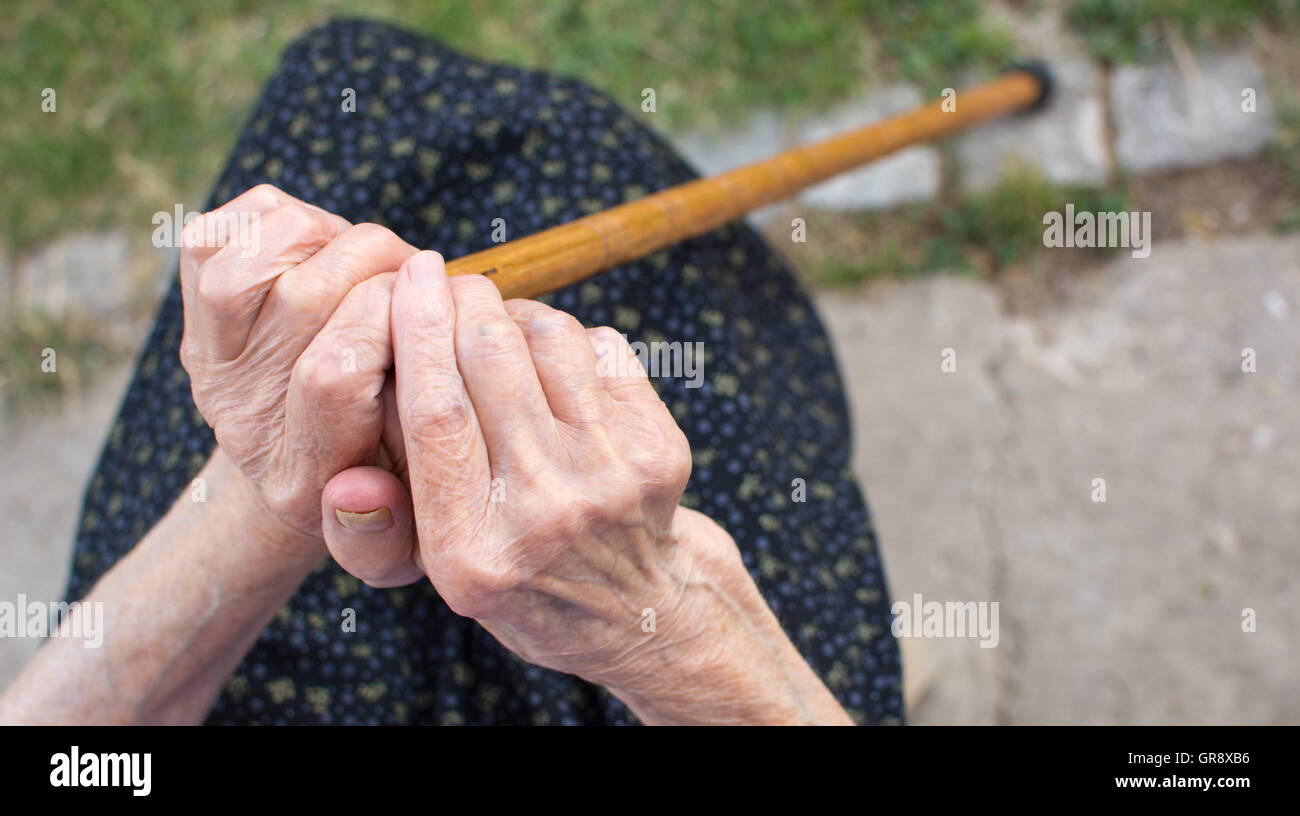 Old woman hands holding a walking cane outdoors Stock Photo