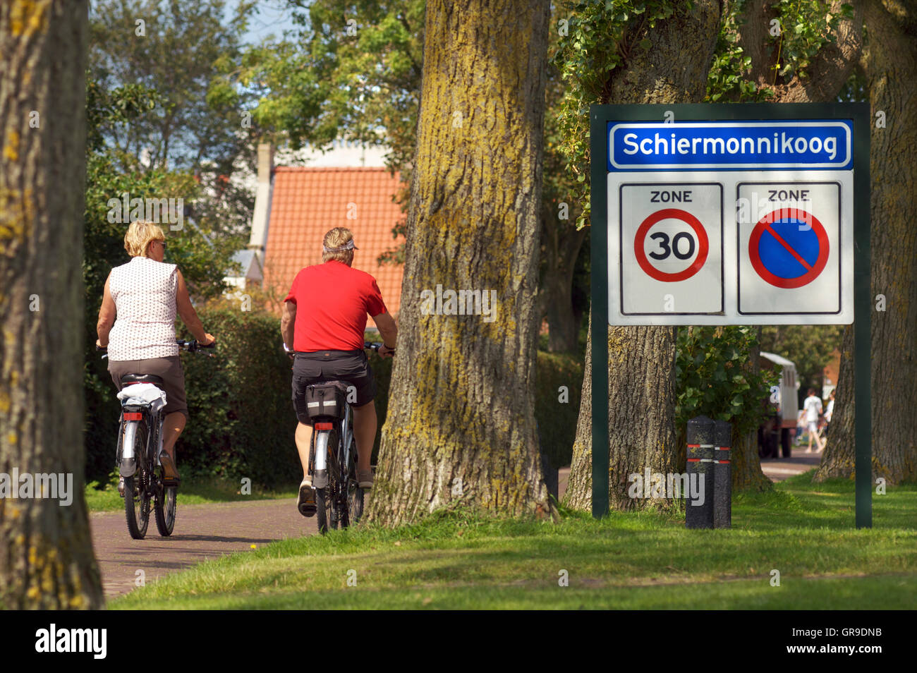 Elderly couple on bicycles riding into the village of Schiermonnigoog on the island Schiermonnikoog Stock Photo