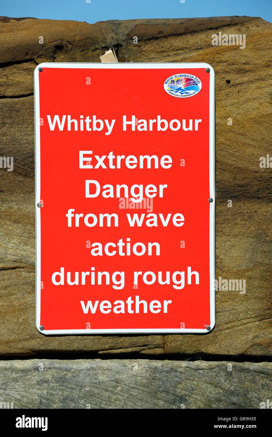 Extreme danger from wave action during rough weather warning sign in Whitby harbour wall North Yorkshire England UK Stock Photo