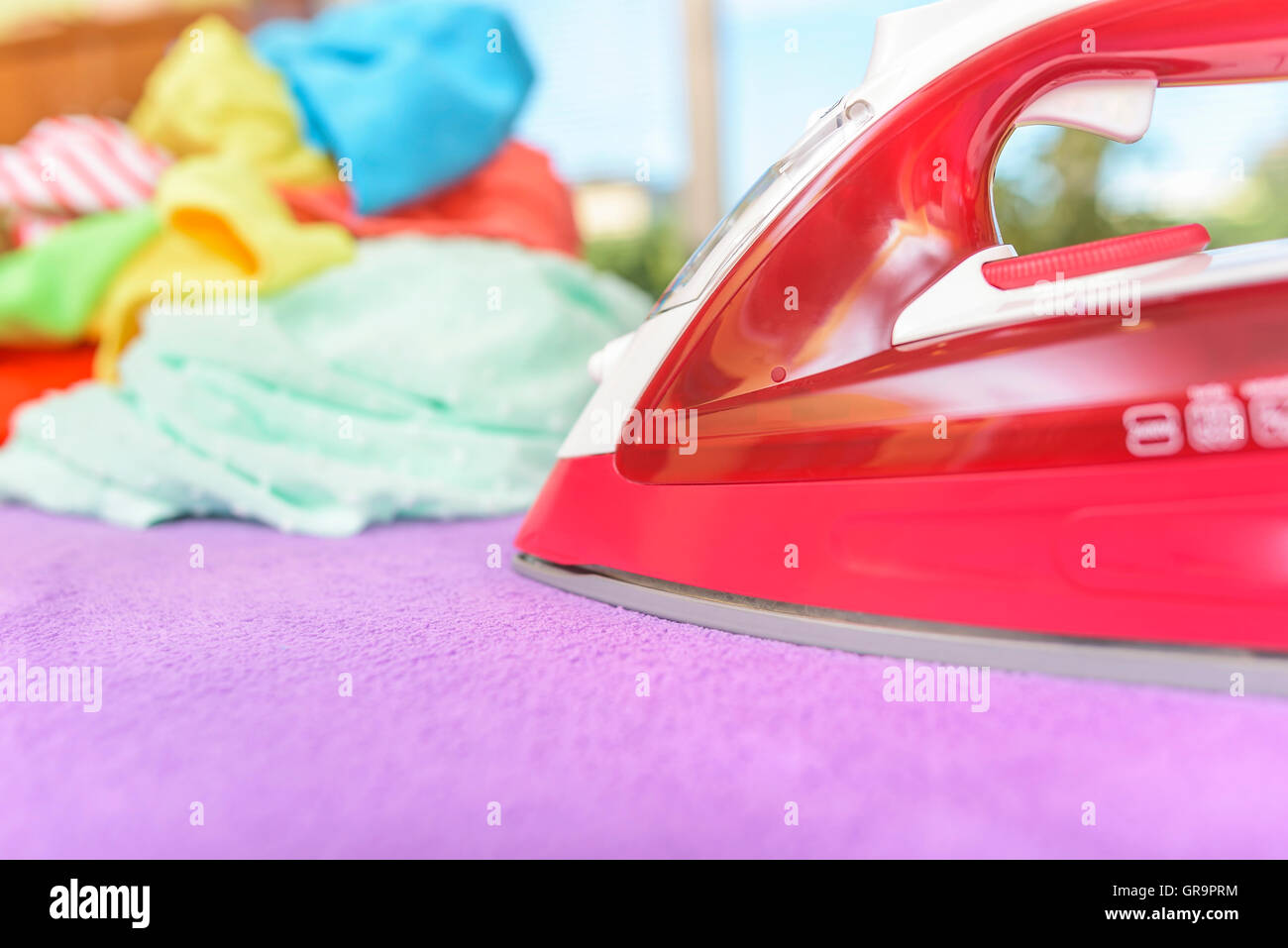 Iron and pile of clothes for ironing. Stock Photo