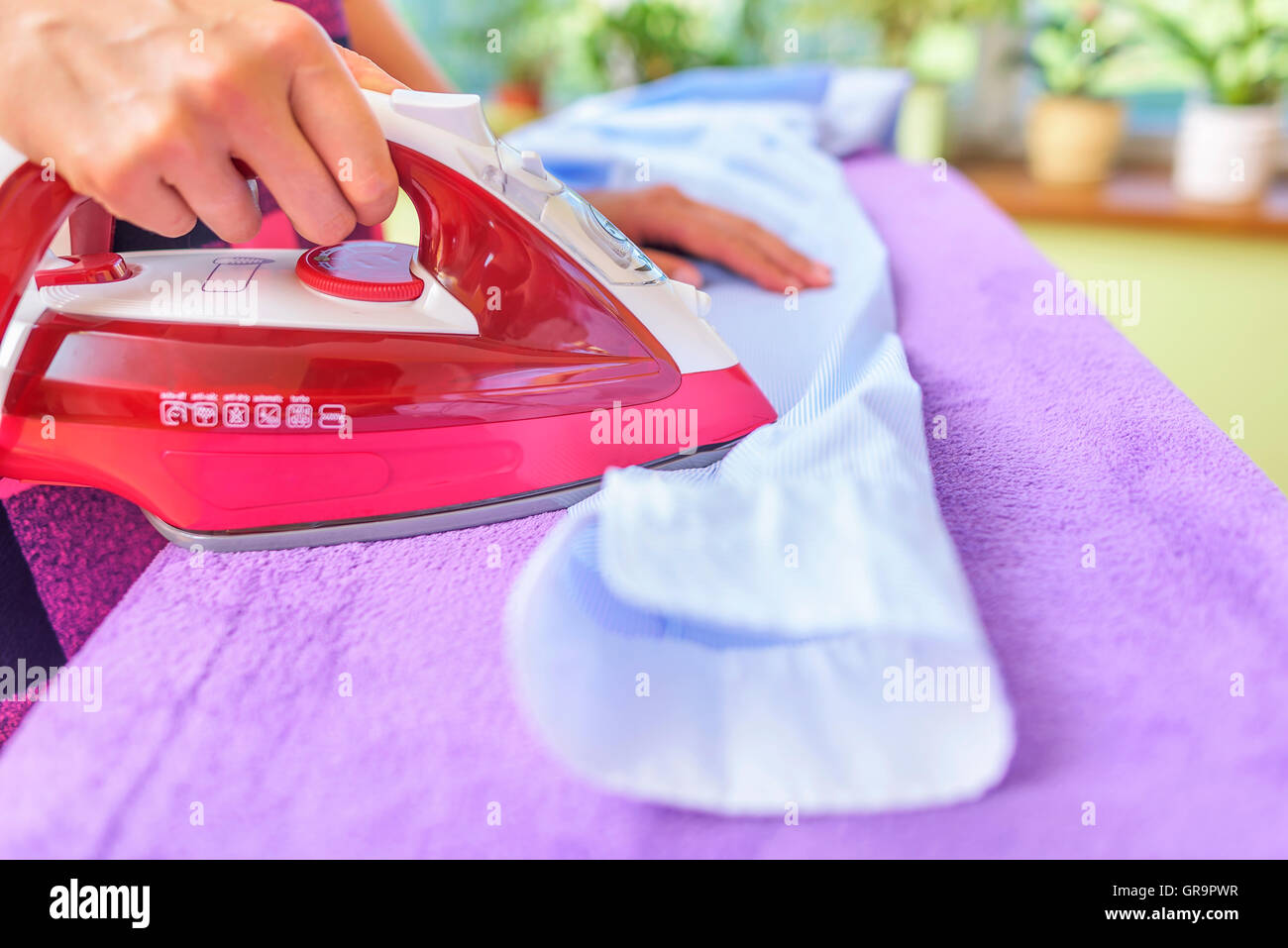 The woman to iron the clothes on an ironing board. Stock Photo