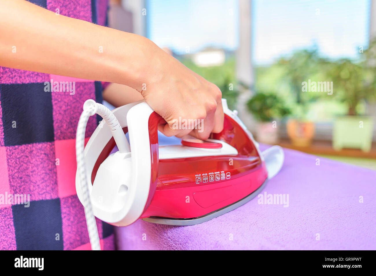 The woman to iron the clothes on an ironing board. Stock Photo