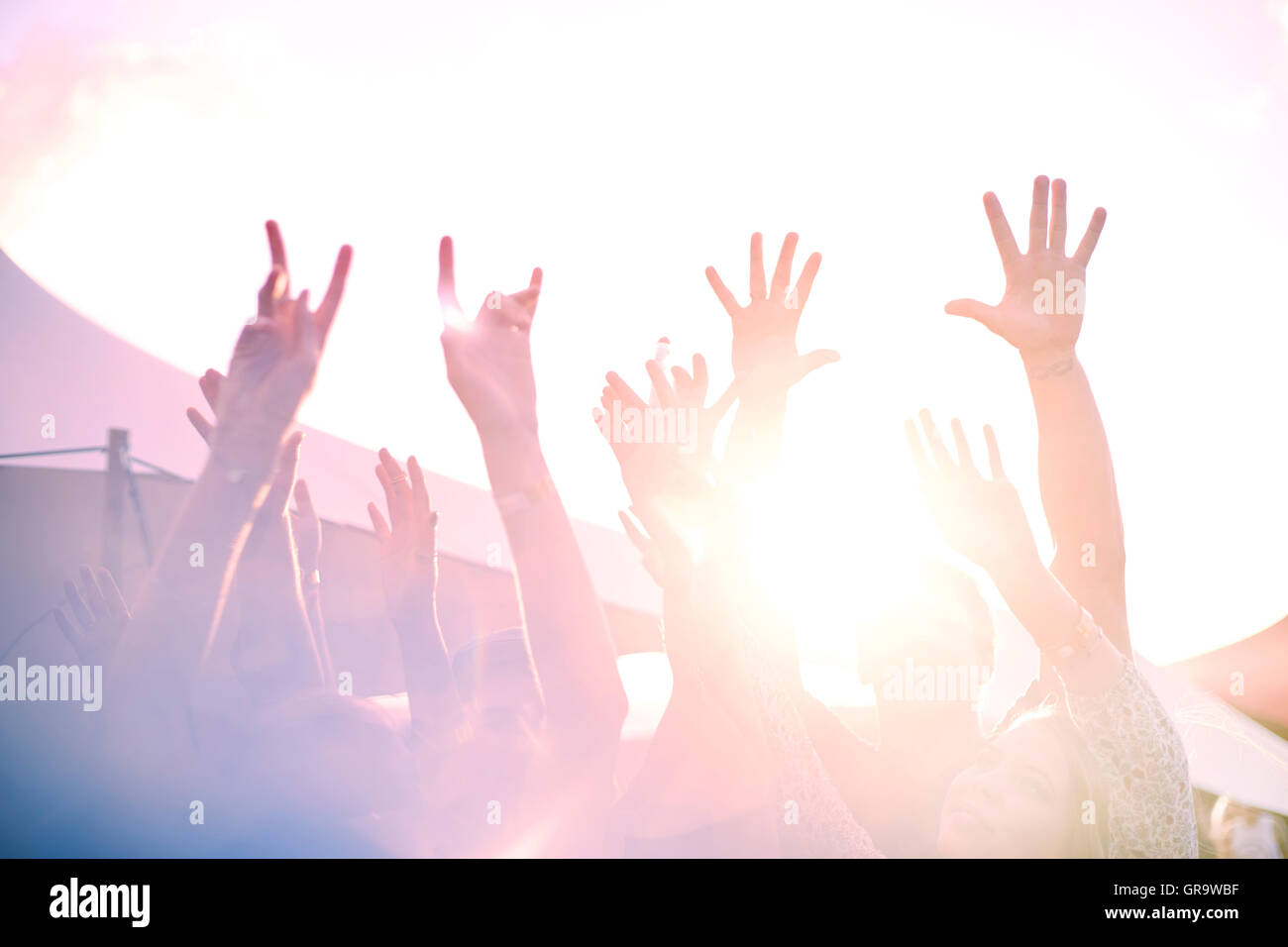 Arms raised cheering at sunny music festival Stock Photo