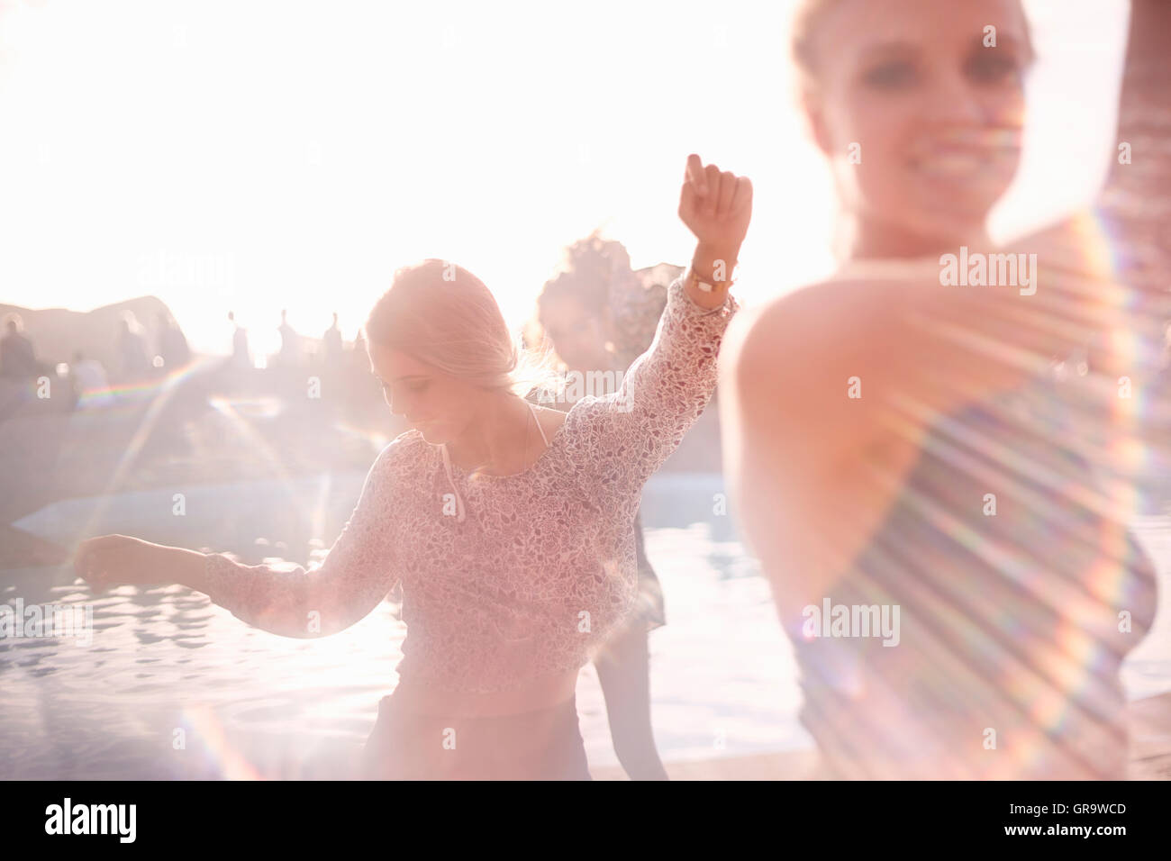Young woman dancing at sunny poolside party Stock Photo