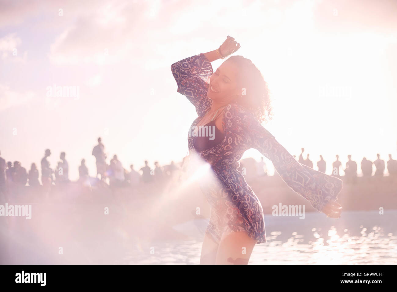Young woman dancing at sunny poolside party Stock Photo