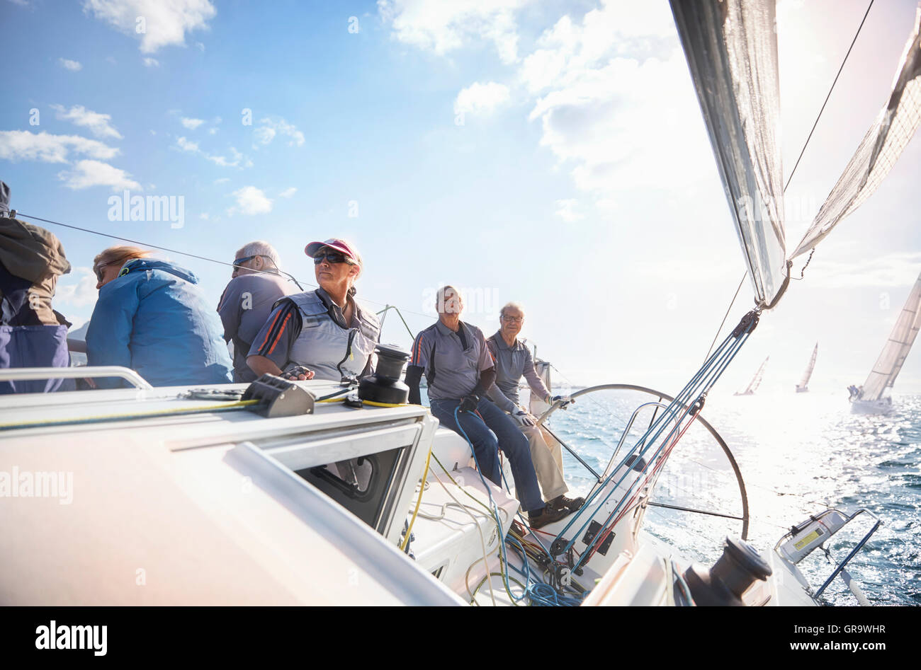 Retired friends on sailboat on sunny ocean Stock Photo