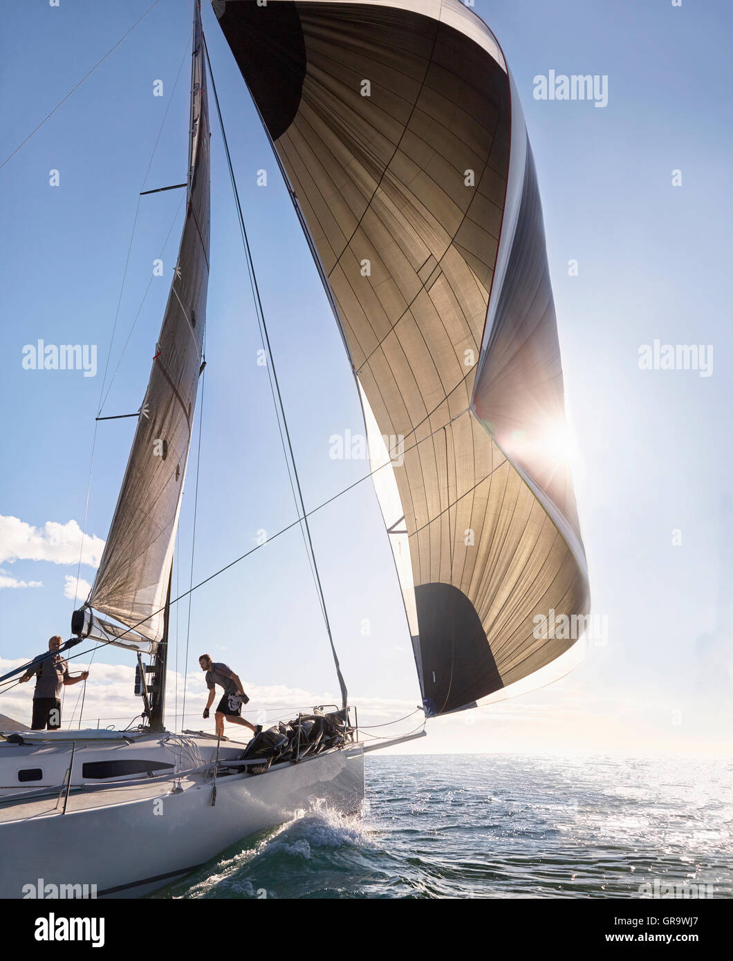 Wind pulling sail on sailboat on sunny ocean Stock Photo