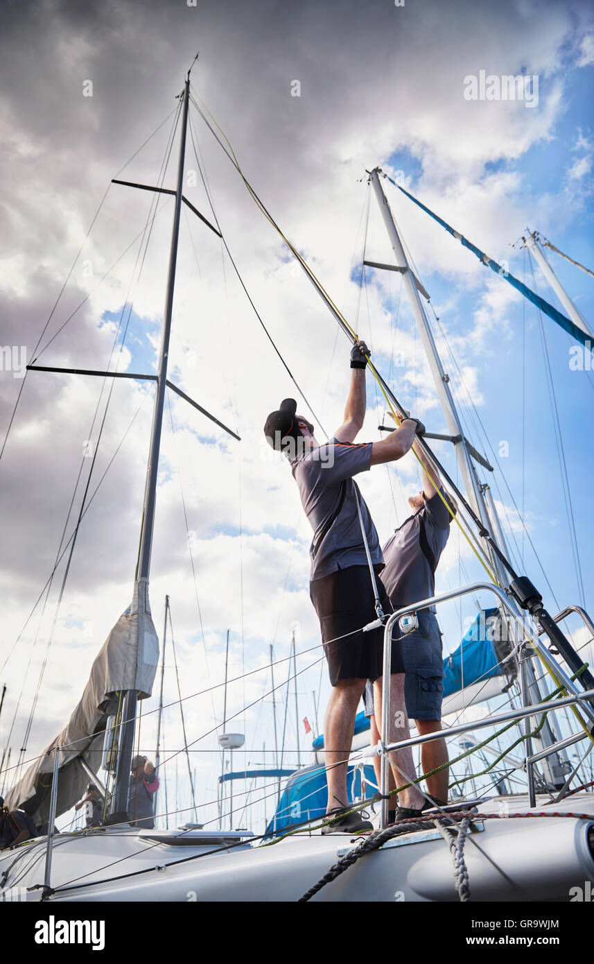 Men adjusting sailing equipment on sailboat Stock Photo