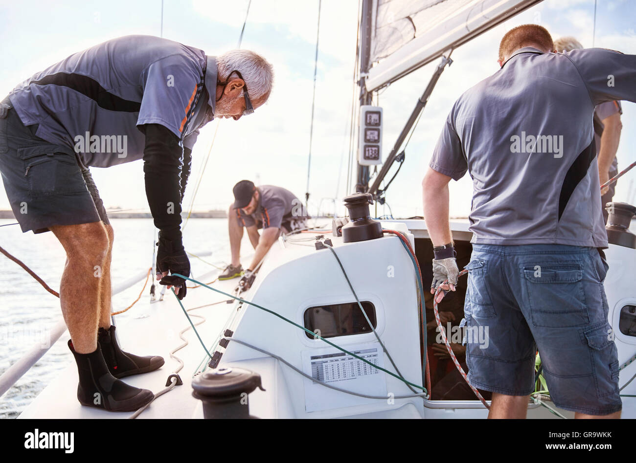 Men sailing adjusting sailboat rigging Stock Photo