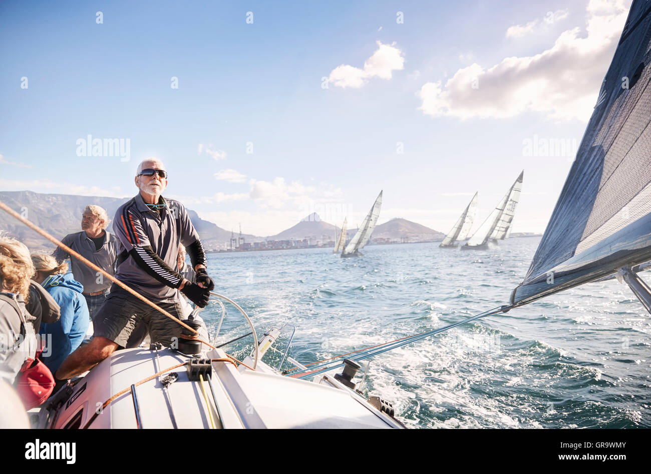 Man adjusting sailboat rigging on sunny ocean Stock Photo