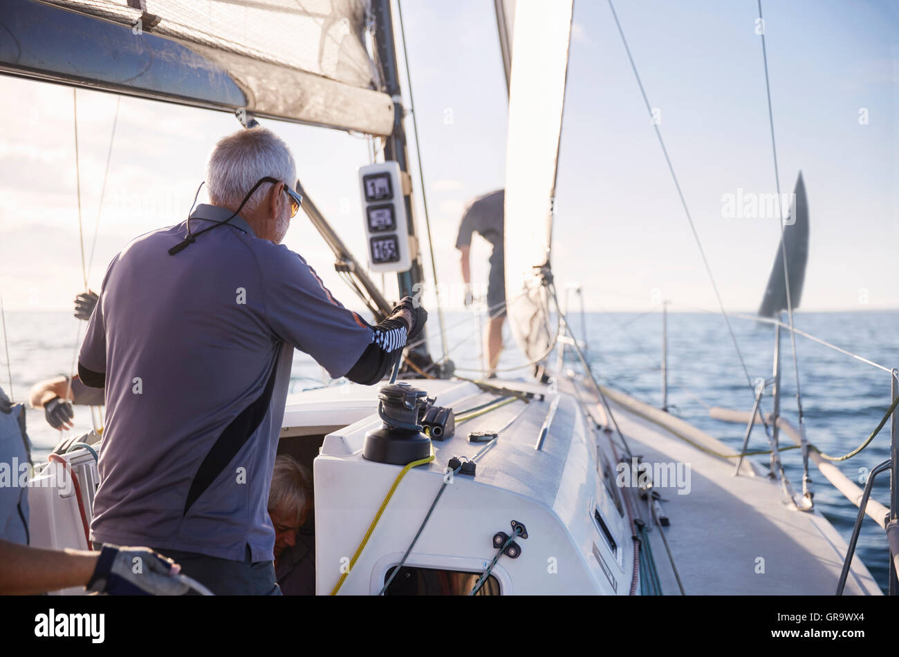 Man adjusting sailing equipment on sailboat Stock Photo