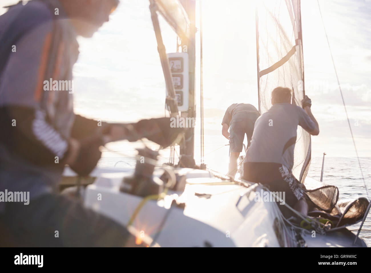 Men adjusting sailing equipment on sailboat Stock Photo