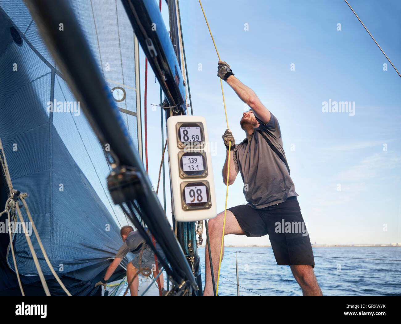 Man adjusting sailing equipment on sailboat Stock Photo