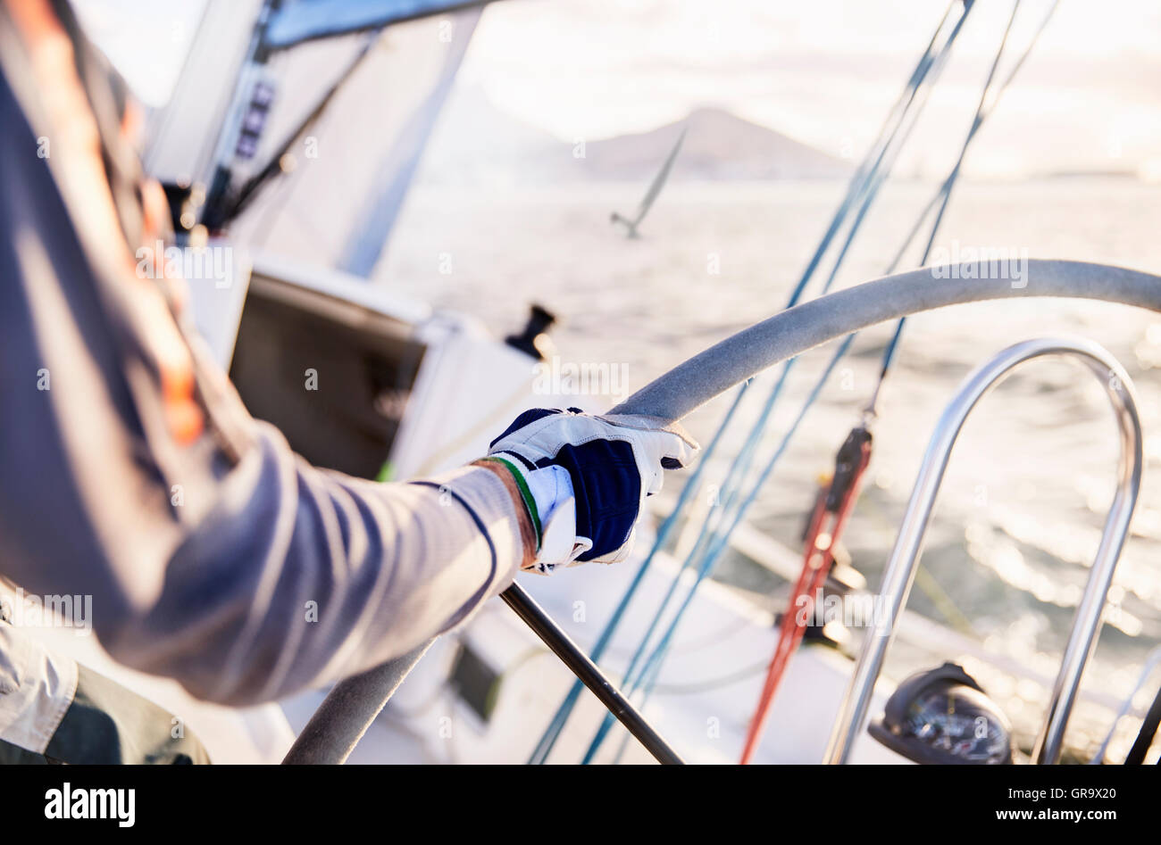 Man sailing steering sailboat at helm Stock Photo