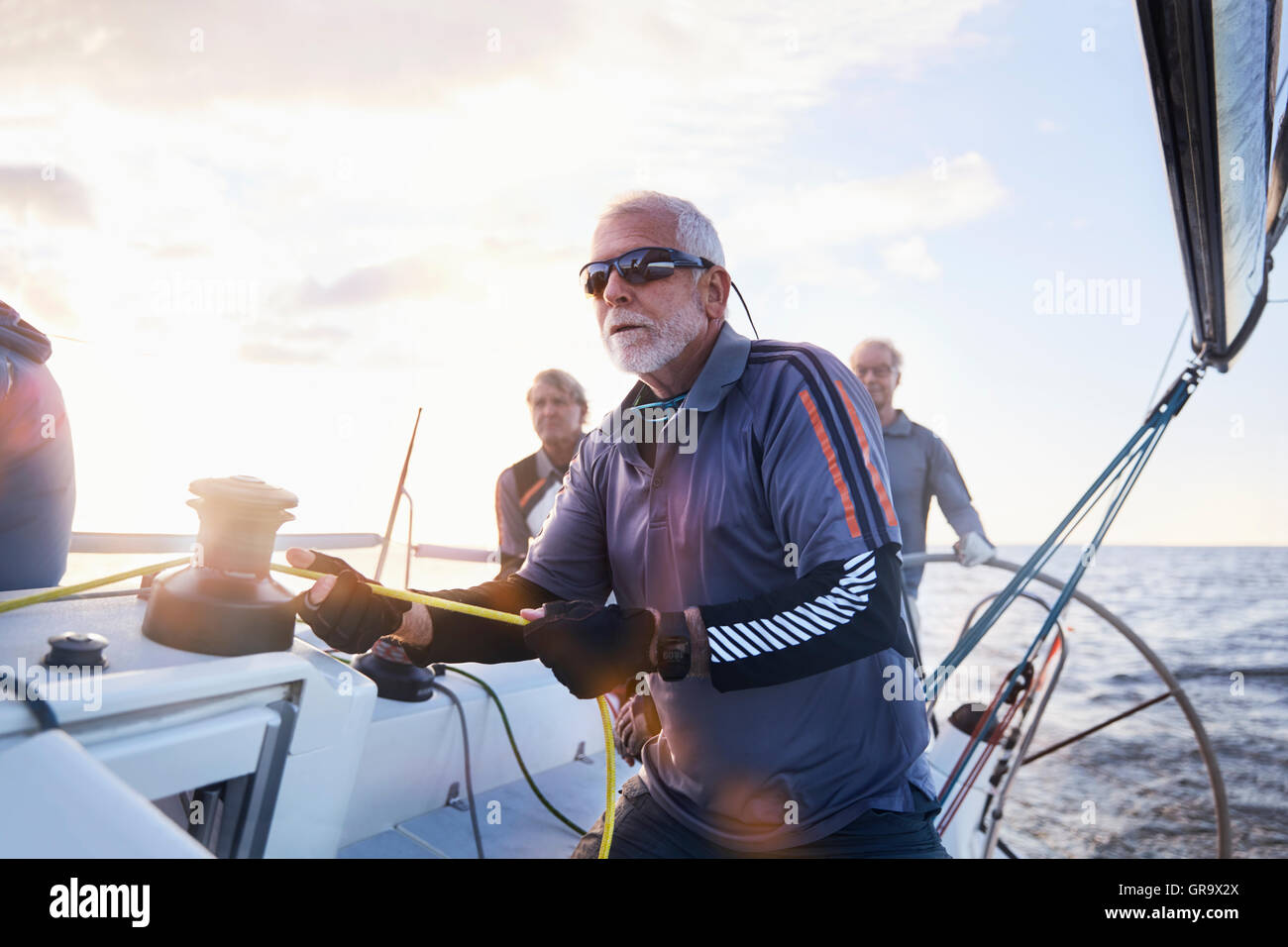 Retired man sailing holding rigging on sailboat Stock Photo