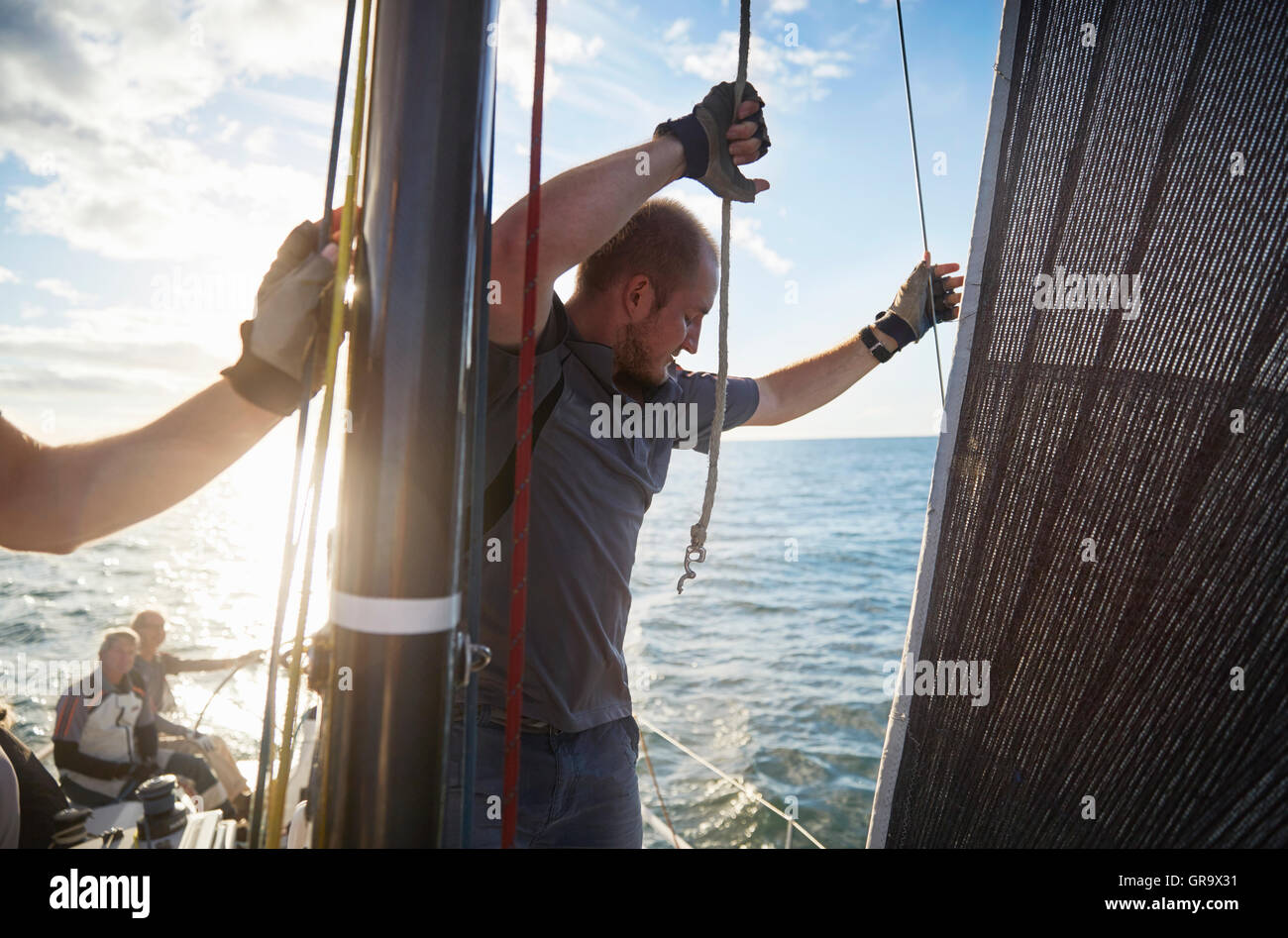 Man adjusting sailing rigging on sailboat Stock Photo