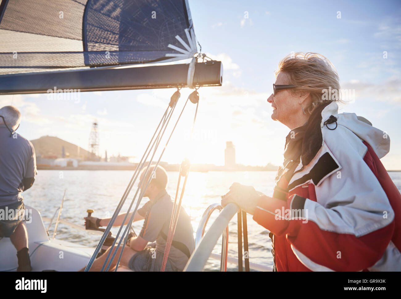 Woman sailing steering sailboat at helm on sunny ocean Stock Photo