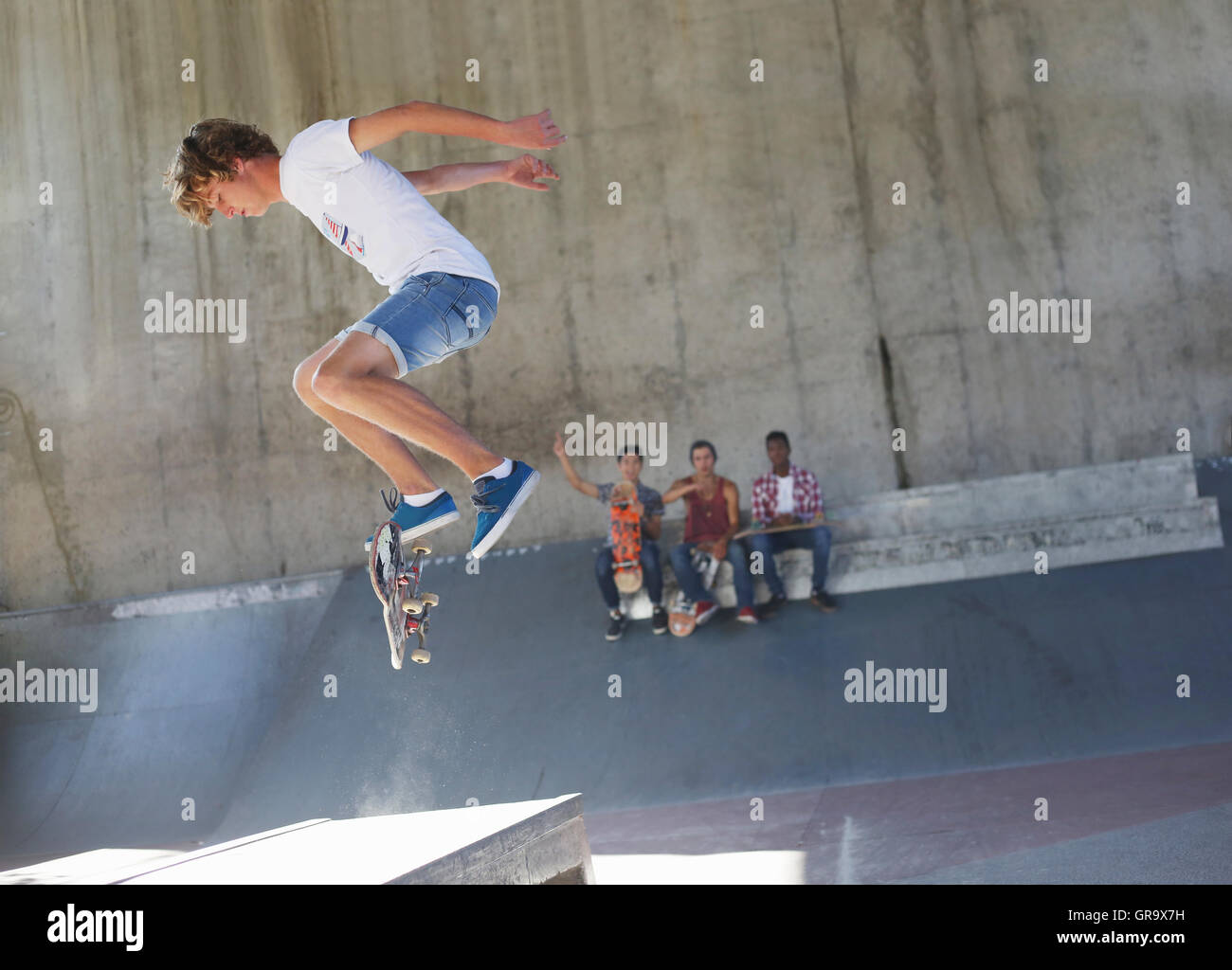 Teenage boy flipping skateboard at skate park Stock Photo