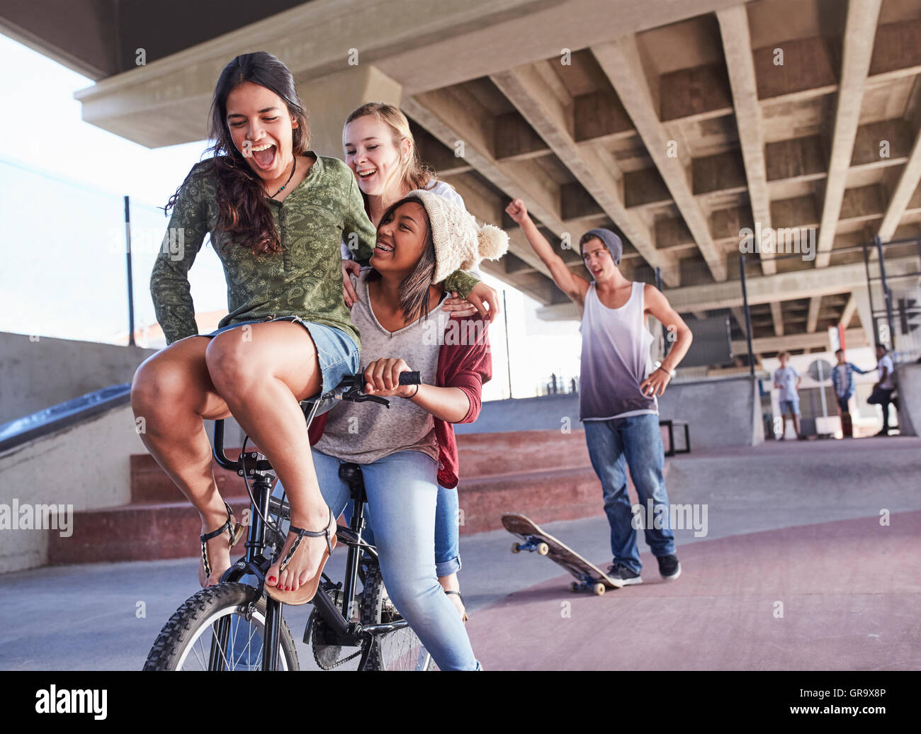 Playful teenage friends riding BMX bicycle and skateboarding at skate park  Stock Photo - Alamy