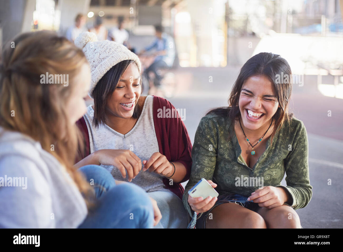 Teenage girls with cell phone laughing and hanging out Stock Photo