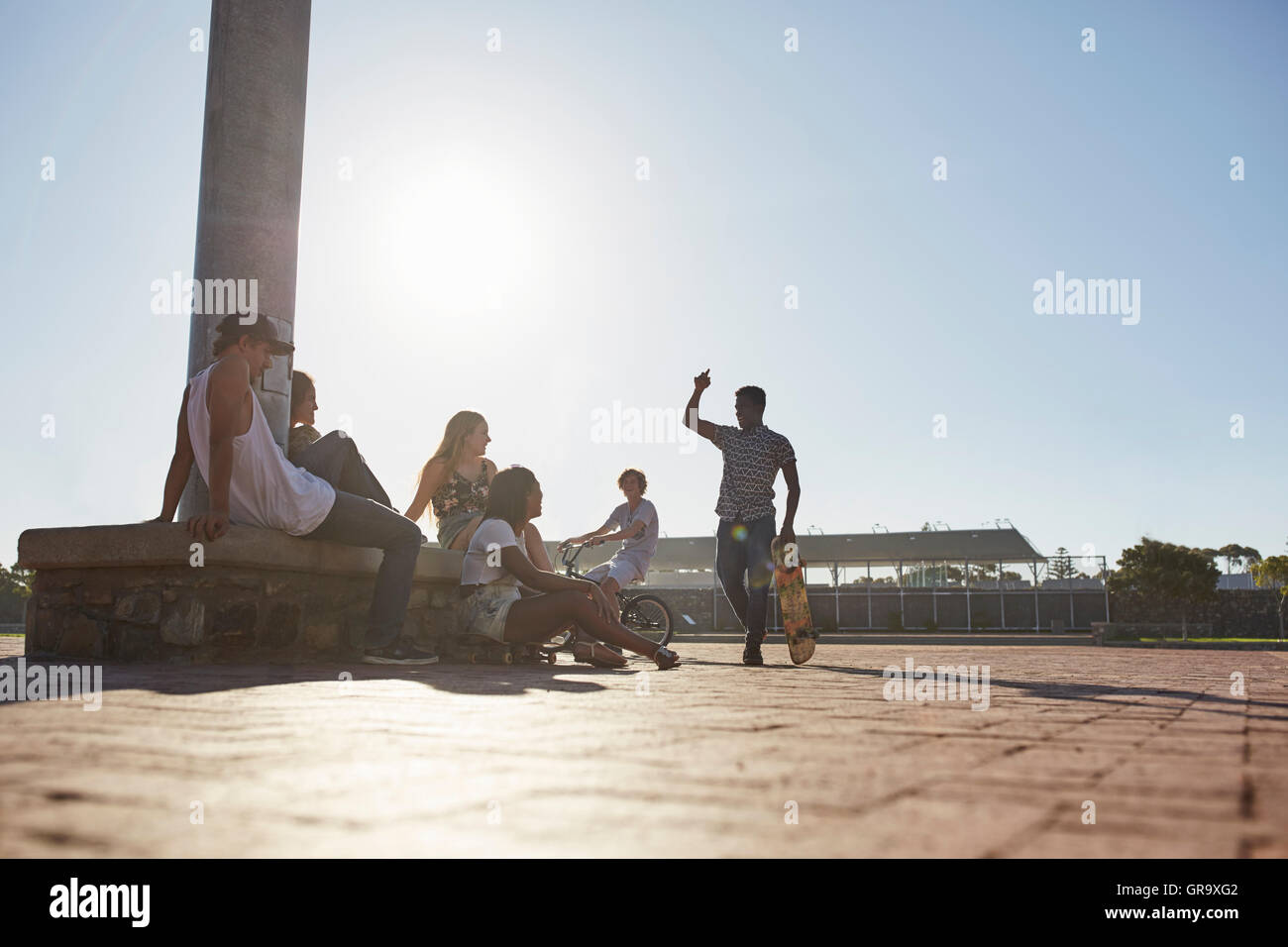 Teenage friends hanging out at sunny skate park Stock Photo