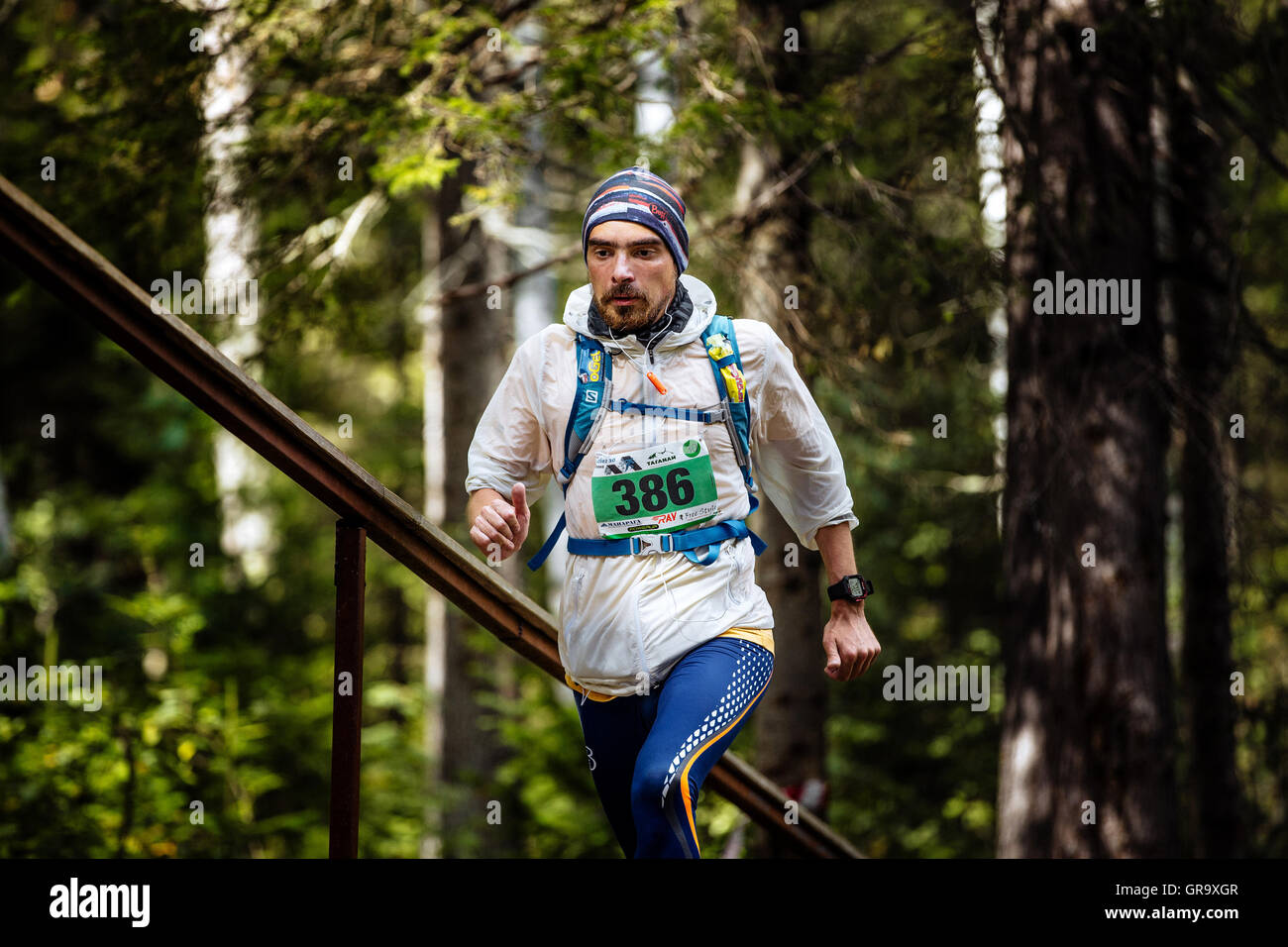 active man athlete running in forest, a backpack on his back and watch on hand during Mountain marathon Stock Photo