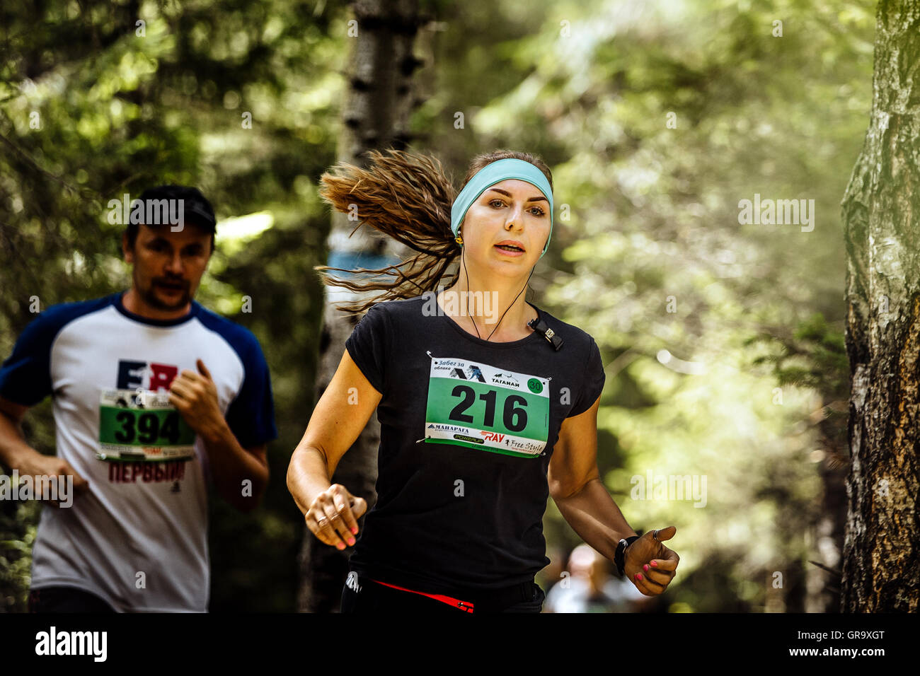 young active woman athlete runs in forest, loose hair during Mountain marathon Stock Photo