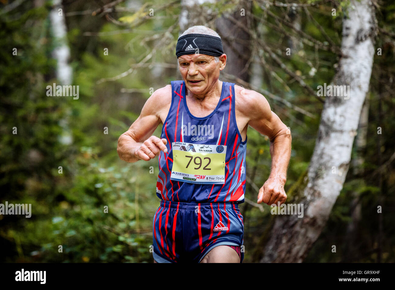 closeup of old active male athlete running in woods during Mountain marathon Stock Photo