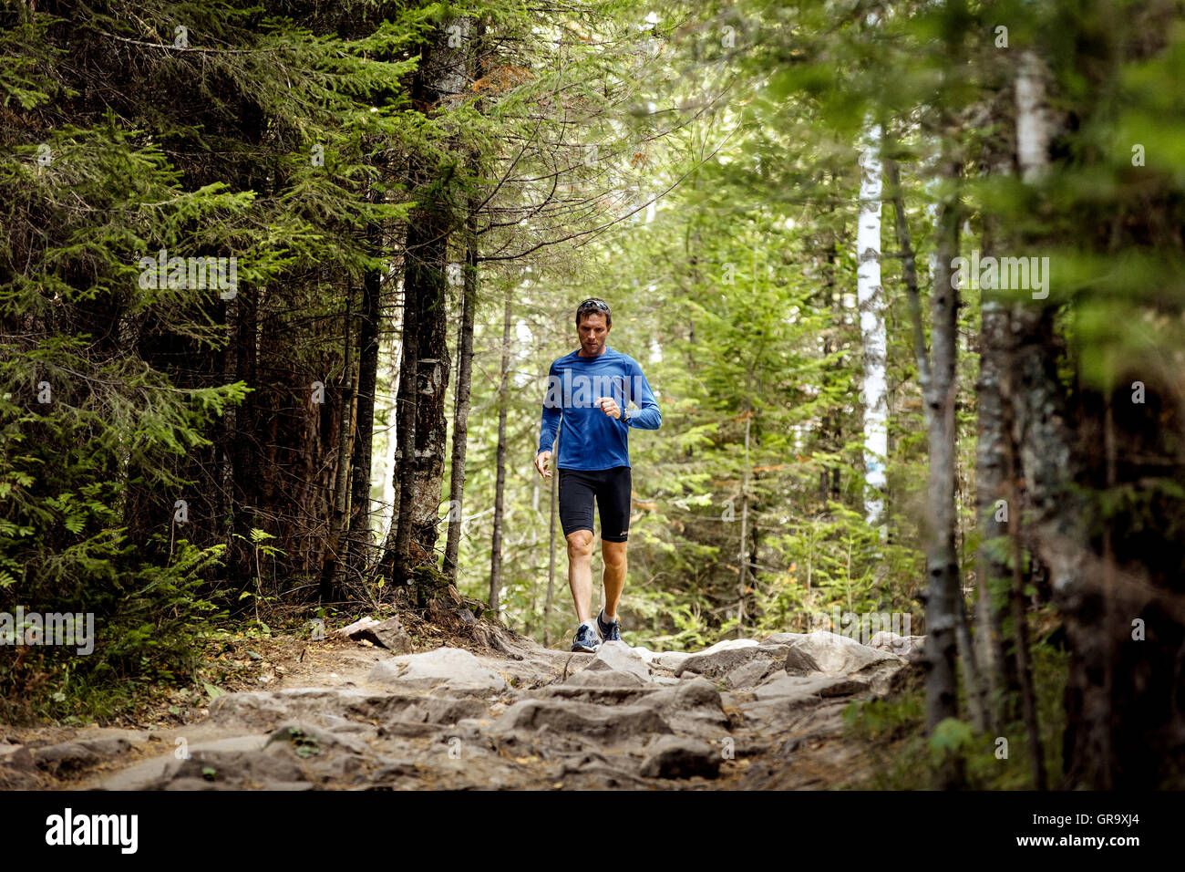 young male athlete active runs rocks trail in woods during Mountain marathon Stock Photo