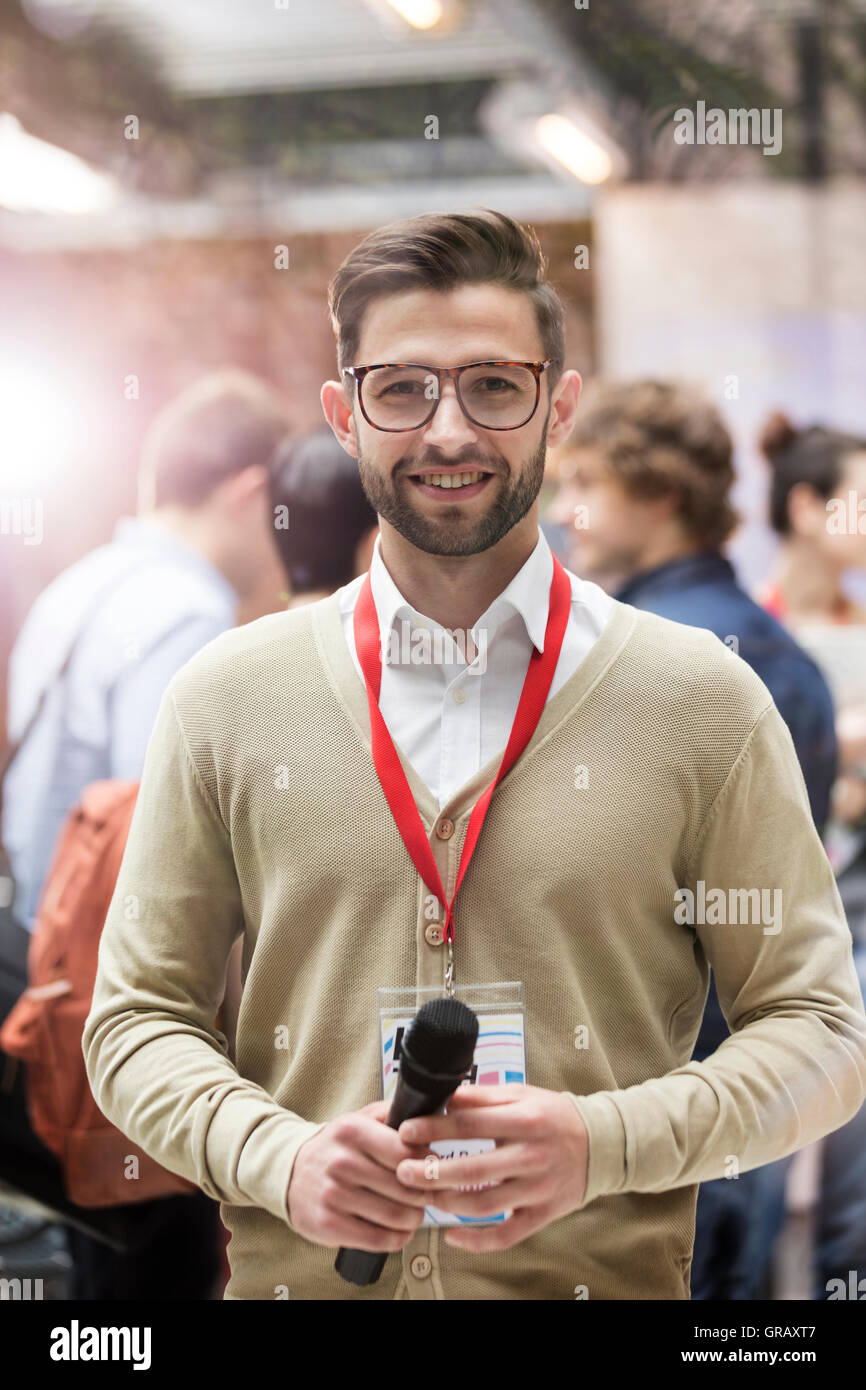 Portrait smiling speaker with microphone at technology conference Stock