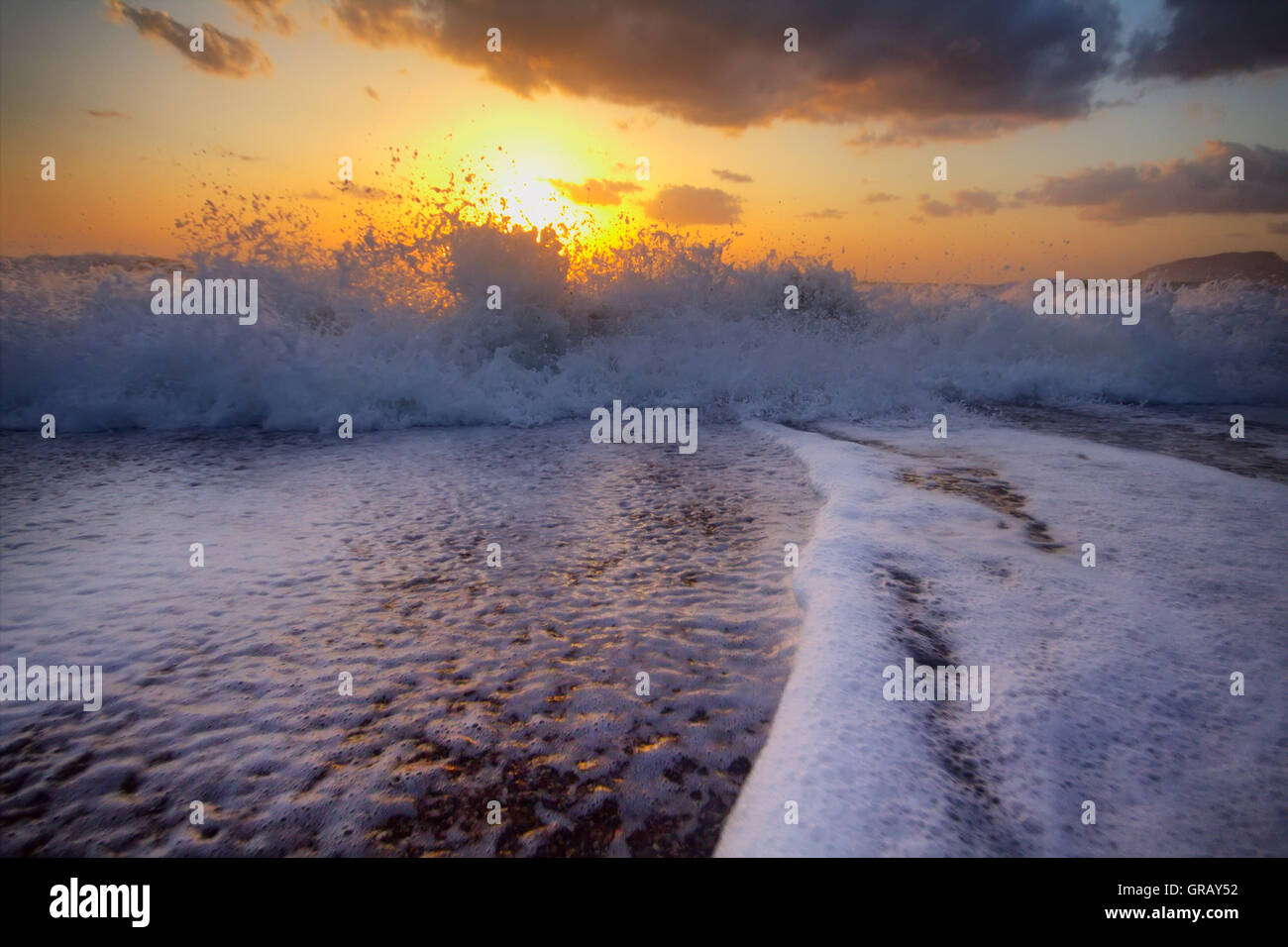 Gentle warm sea on backdrop of enchanting sunset. Foamy surf