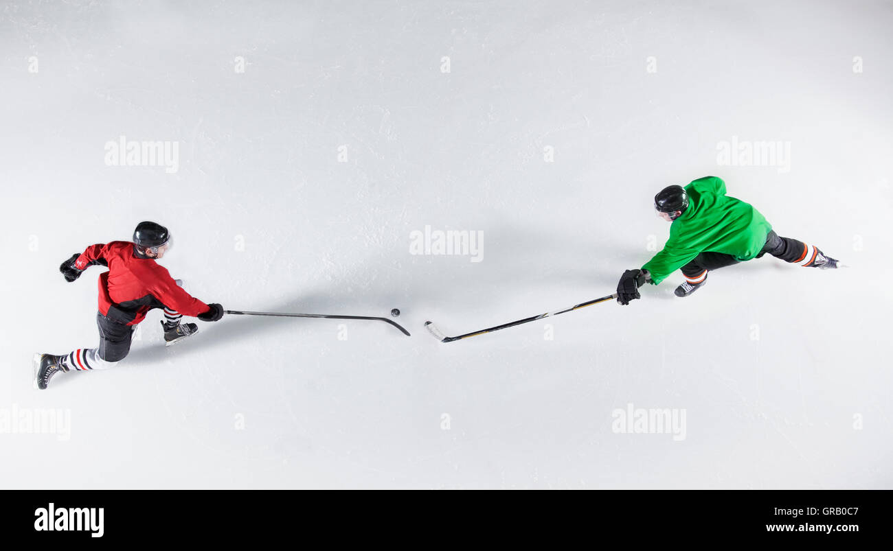 Overhead view hockey opponents reaching for puck on ice Stock Photo Alamy