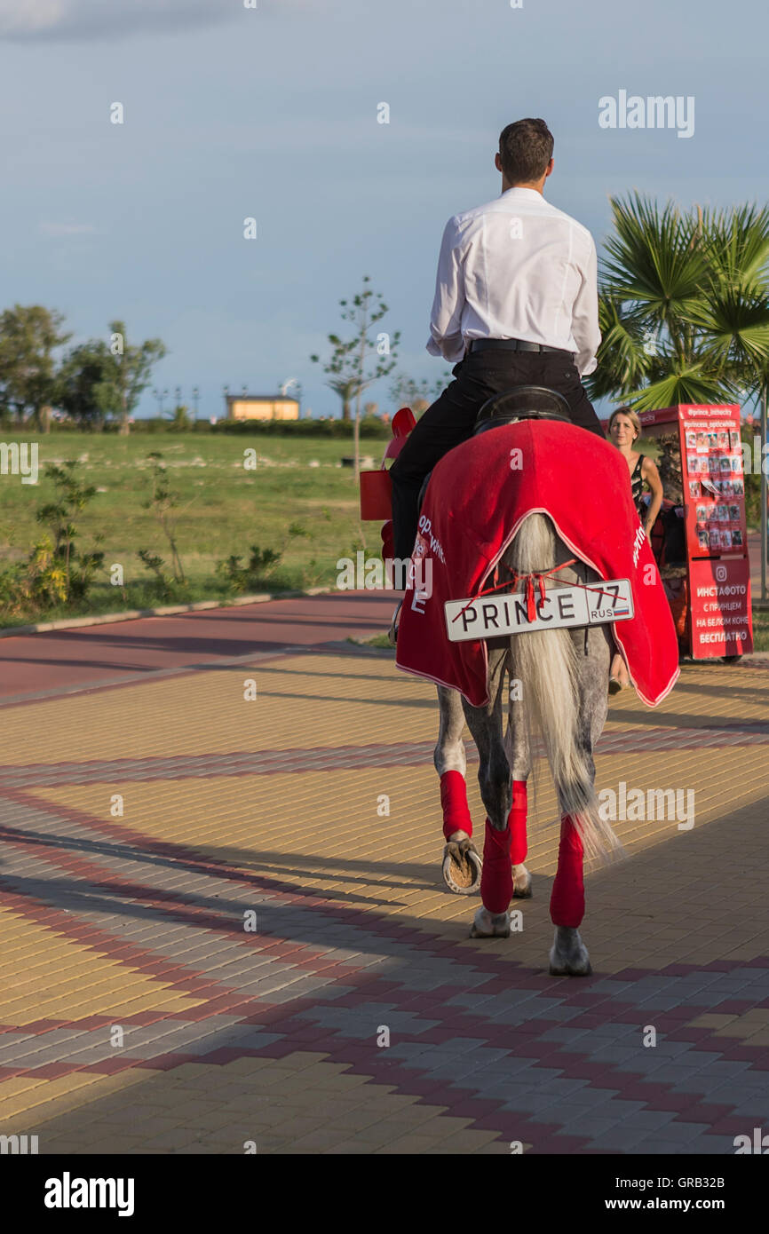 A man on a gray horse in motion, advertises goods, Sochi, the Olympic Village, Russia Stock Photo