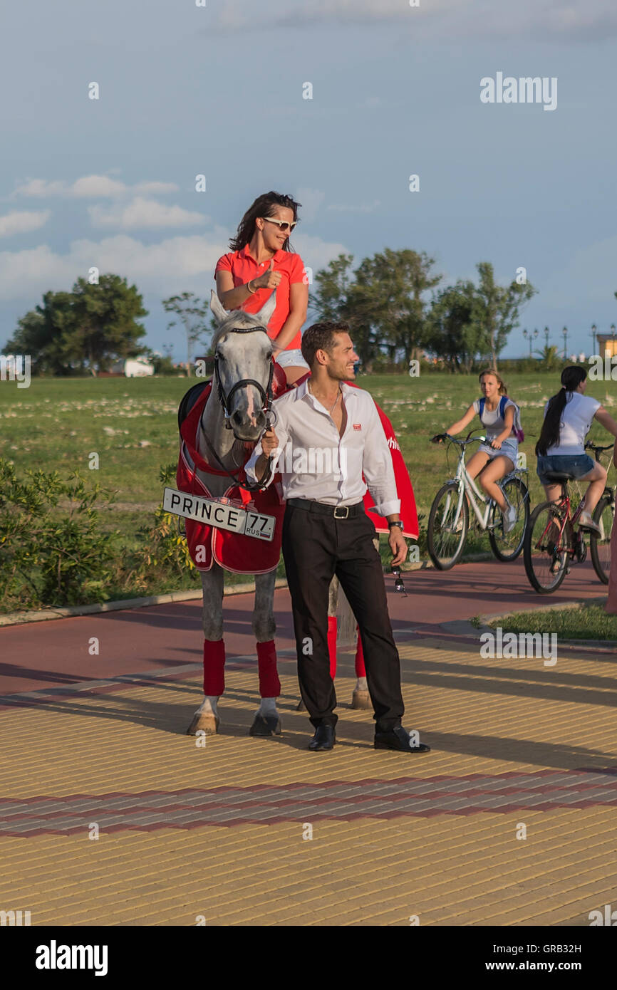 A man on a gray horse in motion, advertises goods, Sochi, the Olympic Village, Russia Stock Photo