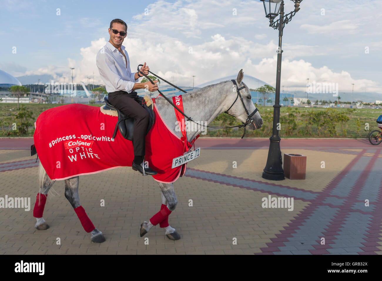 A man on a gray horse in motion, advertises goods, Sochi, the Olympic Village, Russia Stock Photo