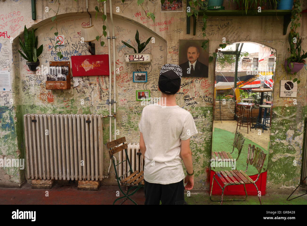 Teenage boy looking at art work and graffiti in the Szimpla kert Ruin Bar, Budapest, Hungary Stock Photo