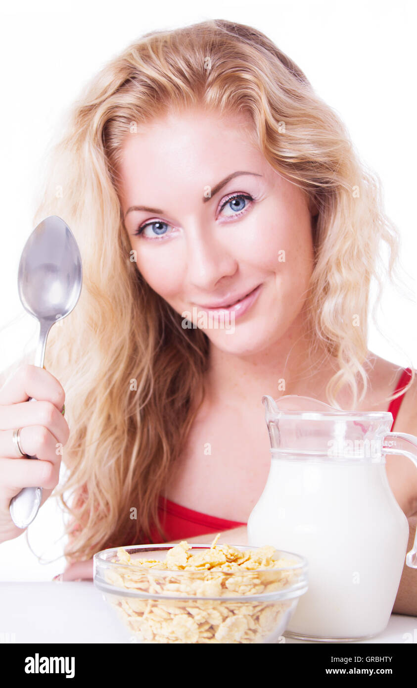 Smiling woman with spoon, milk and corn-falkes Stock Photo