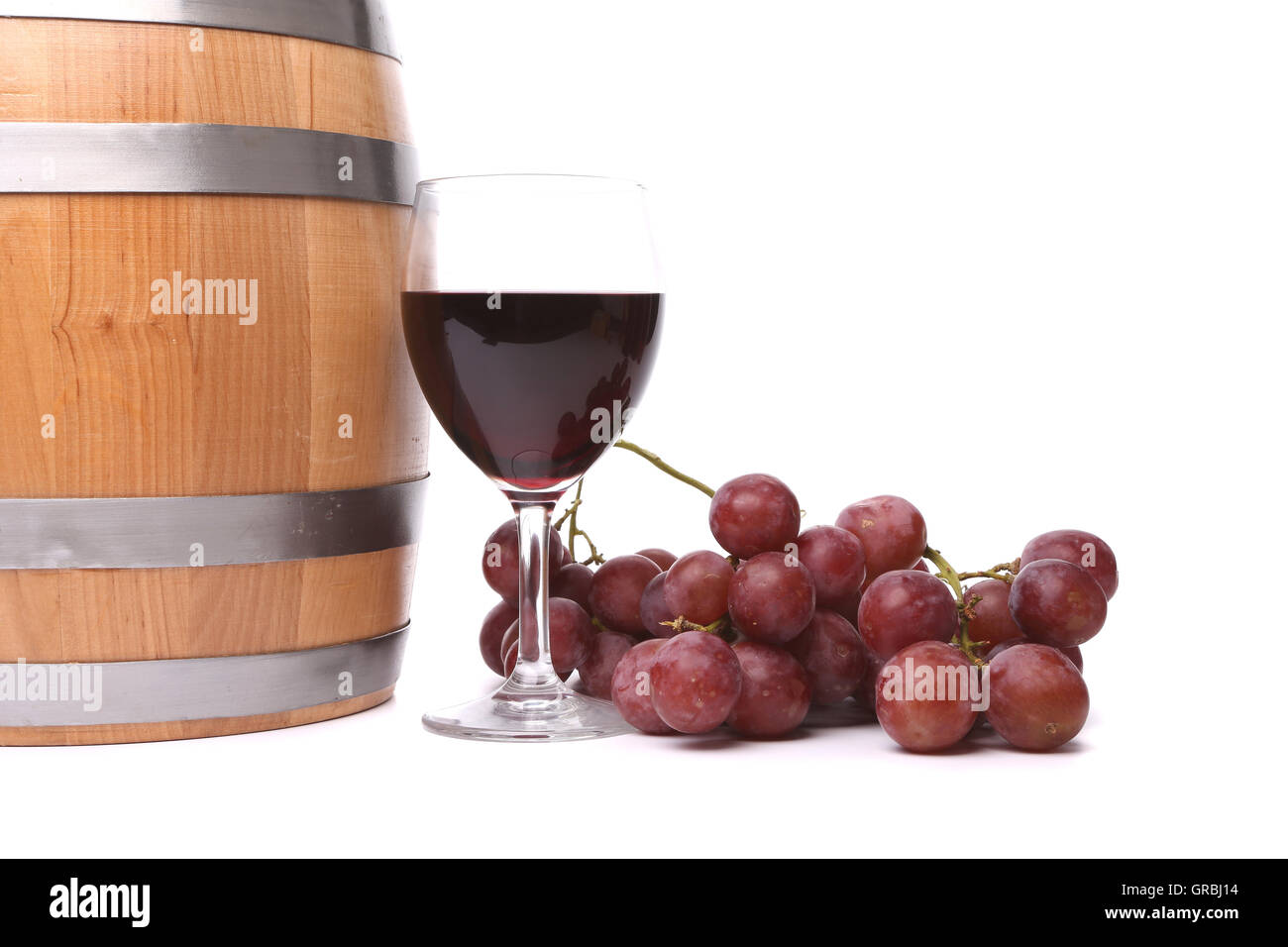 A glass of red wine with grapes and barrel. Stock Photo
