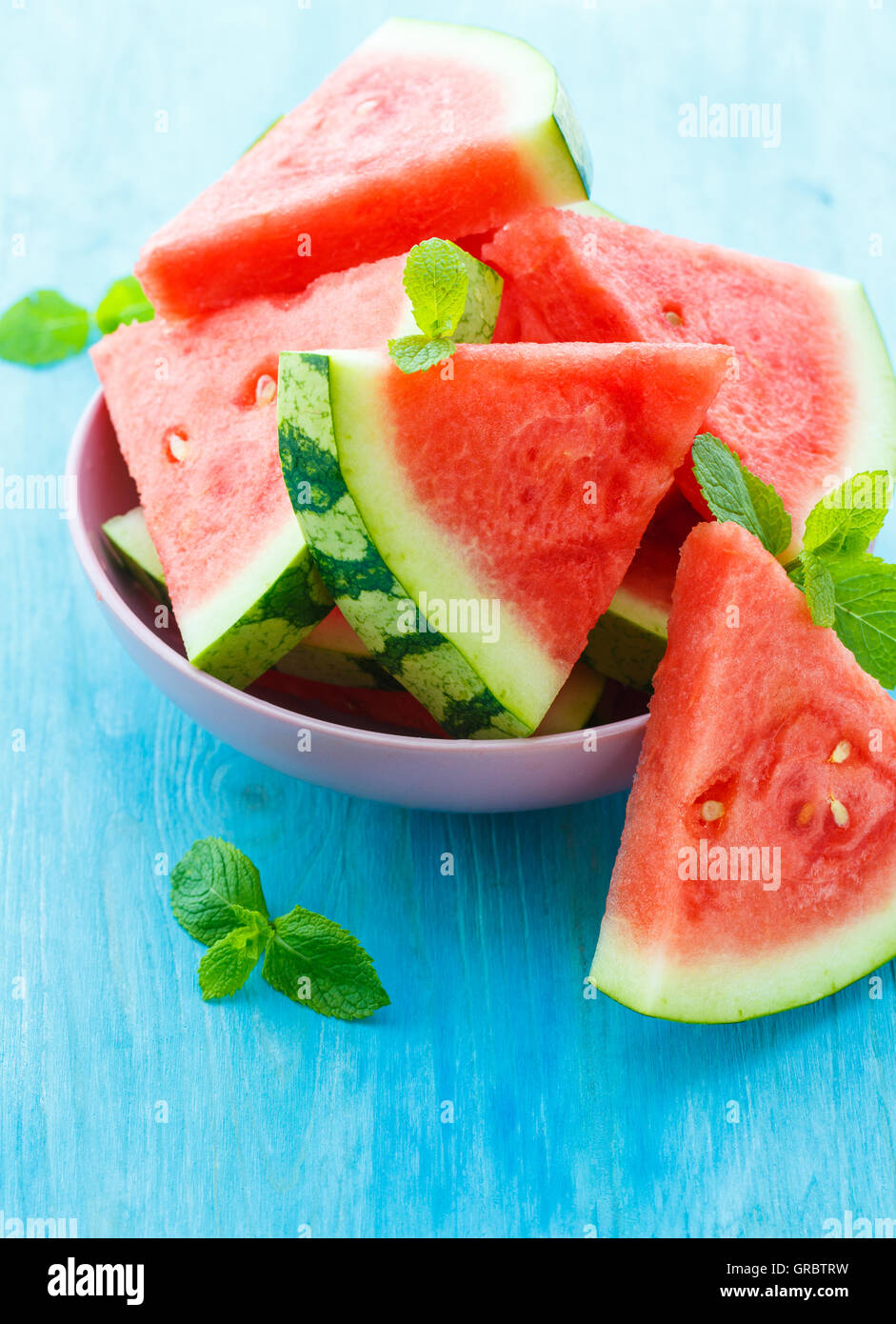 Triangular slices of fresh watermelon with mint on blue wooden background Stock Photo