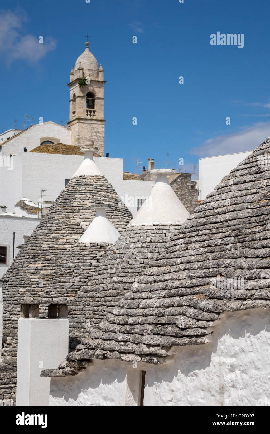 Trulli Roofs In The Foreground, Church Tower In The Background, Alberobello, Apulia, Italy Stock Photo