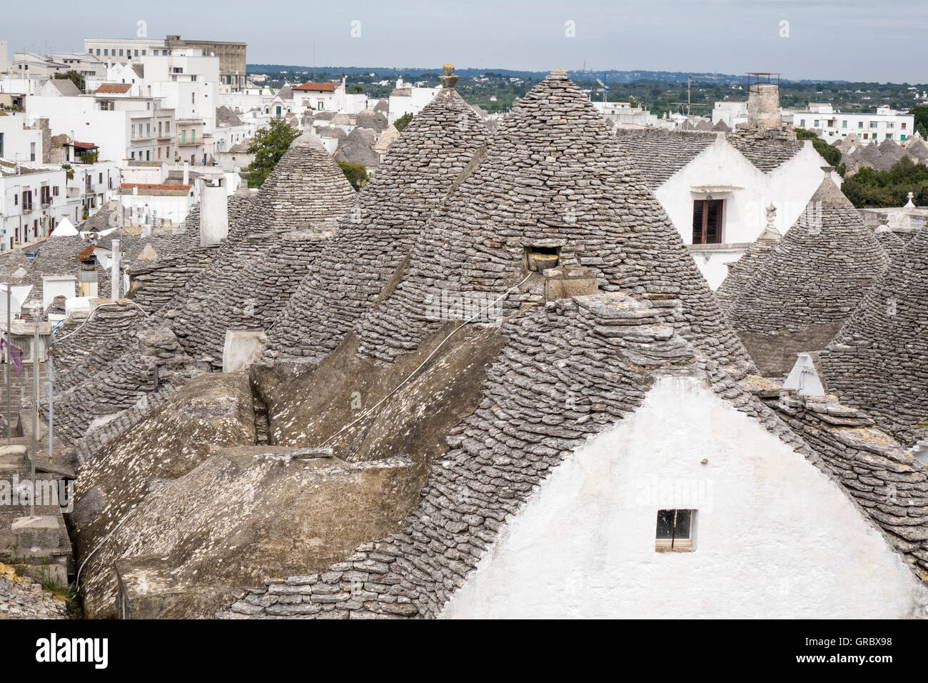 Trulli In The Foreground, Modern Houses In The Background, Alberobello, Apulia, Italy Stock Photo