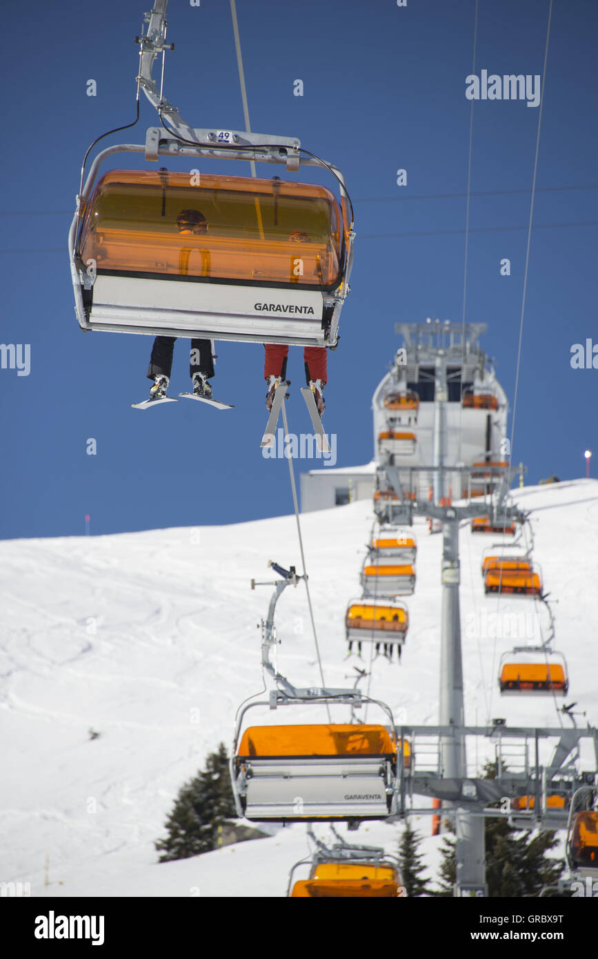 Chairlift With Orange Weather Protectors, Legs With Skis, Blue Sky Stock Photo