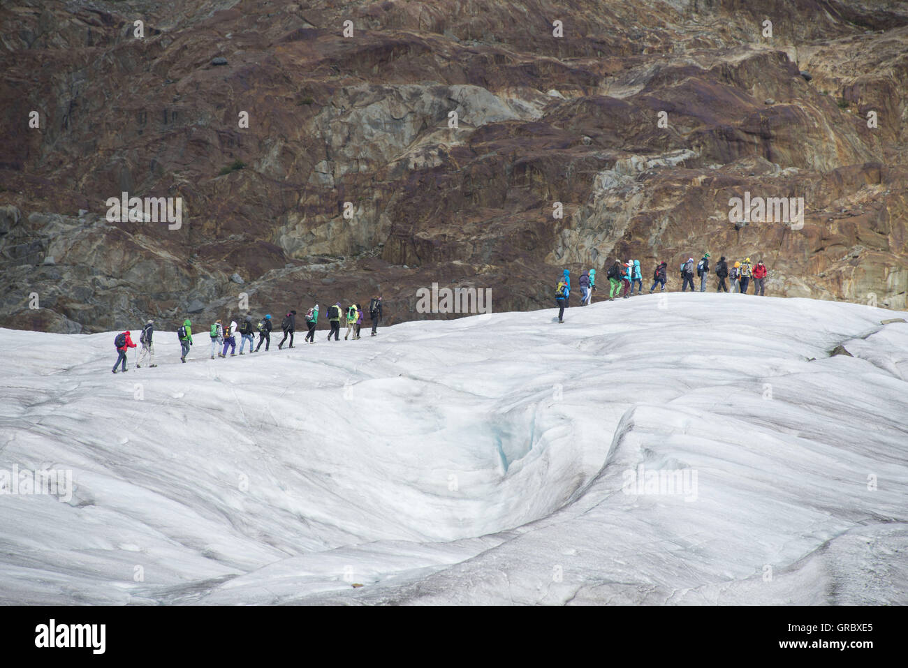 A Group Of People Walks On The Aletsch Glacier Stock Photo