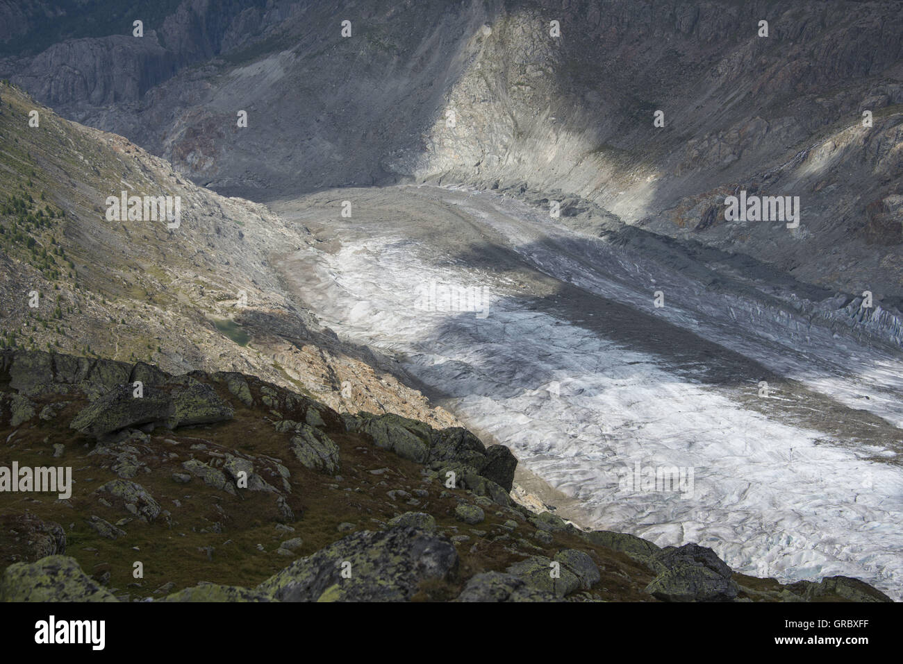 View Over Rocks On The Partly Sunny Great Aletsch Glacier, Prominent Medial Moraine Stock Photo