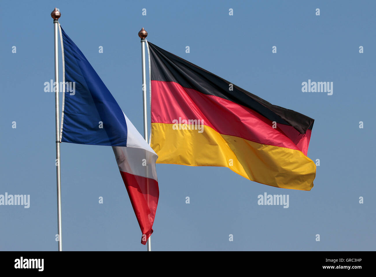 German Flag Blowing In The Wind Whlie French Flag Hangs Down In Still Air Stock Photo