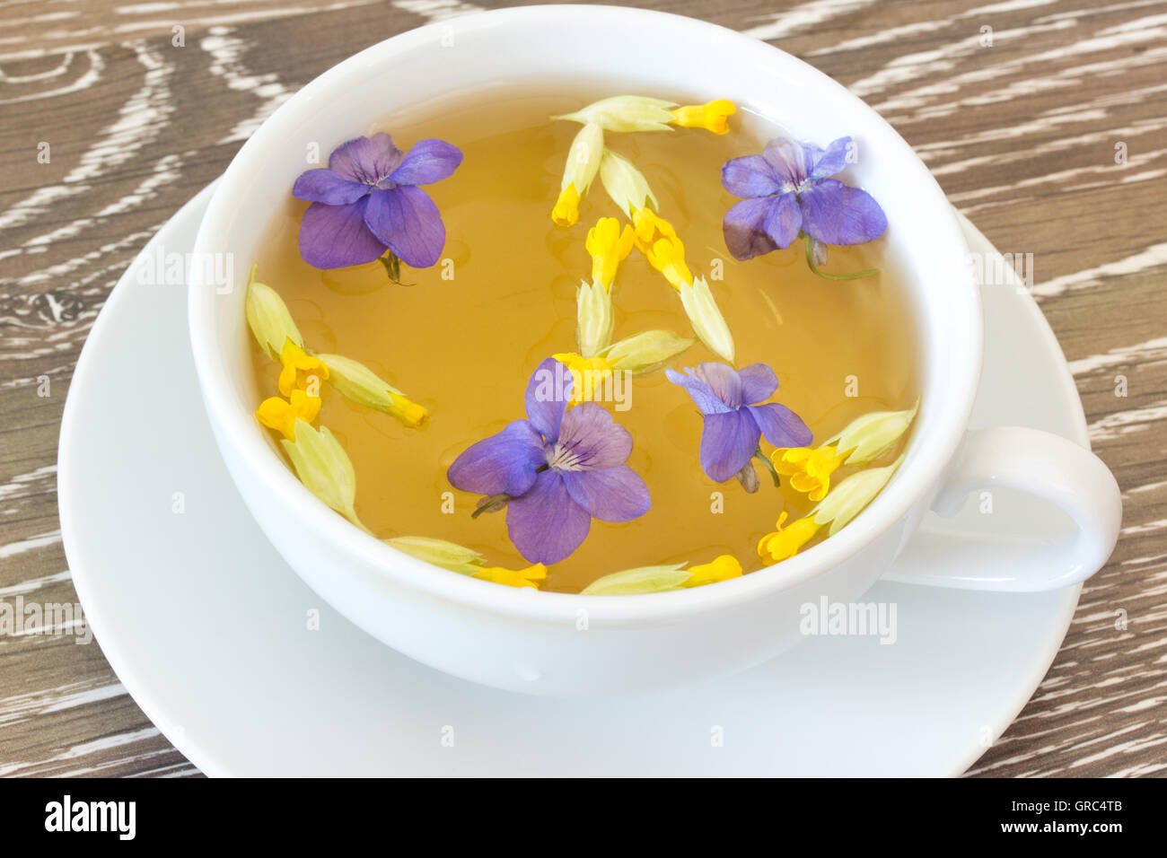 Cup Of Herb Tea With Violets And Cowslips On Wooden Background Stock Photo