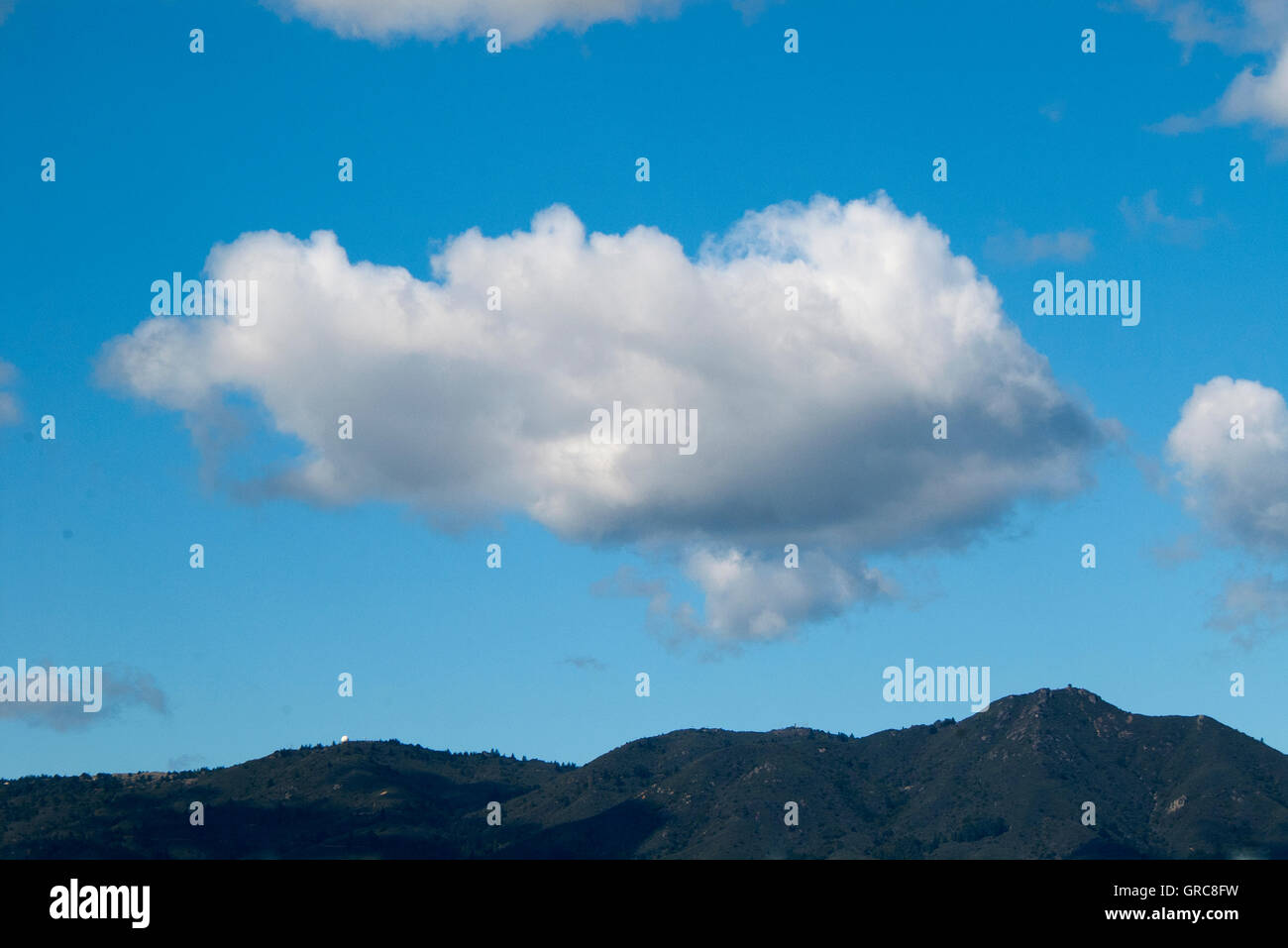 Cumulus cloud formation in blue sky over land Stock Photo