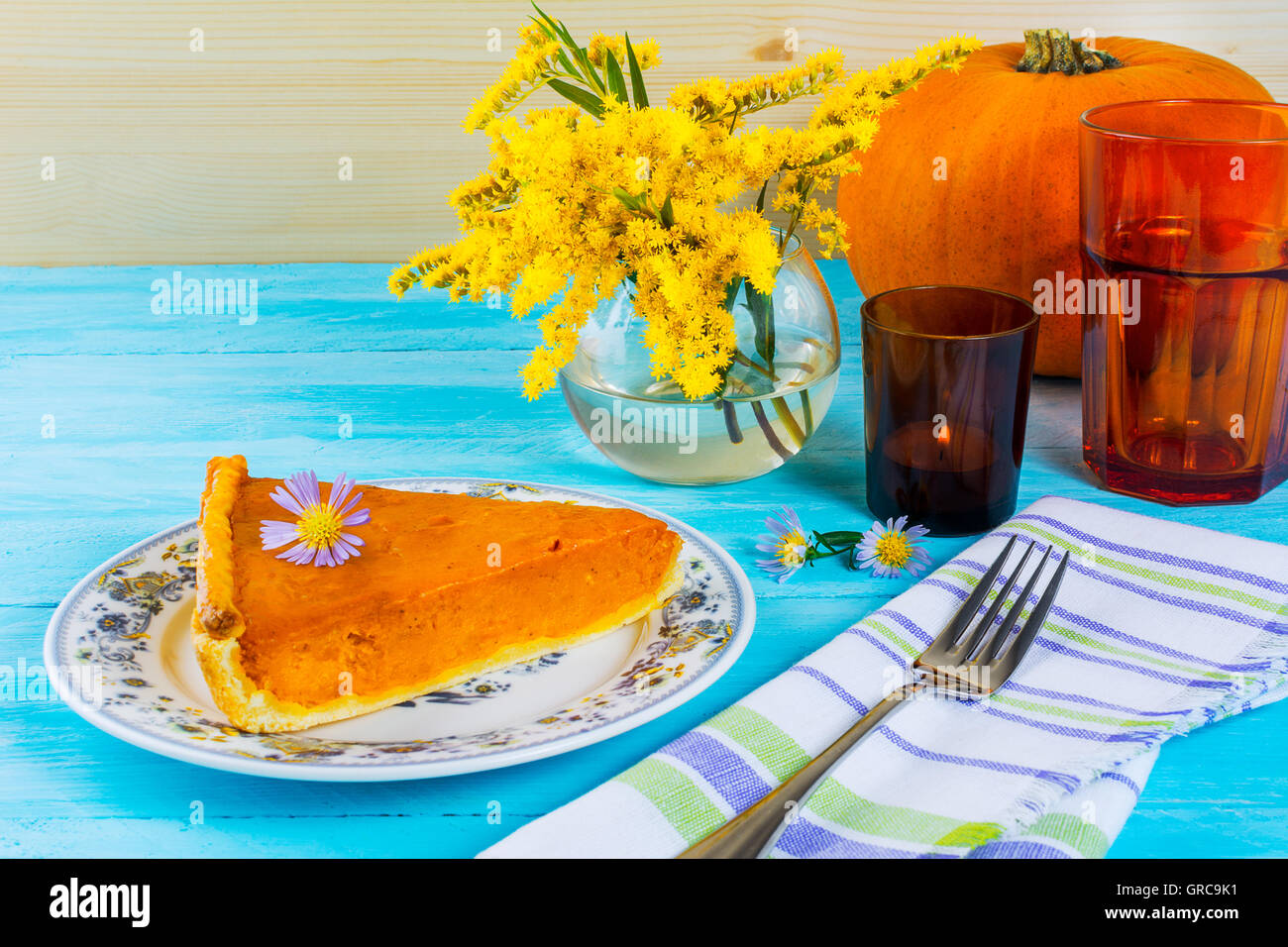 Thanksgiving pumpkin pie slice on the blue wooden table. Traditional Thanksgiving pumpkin pastry. Stock Photo