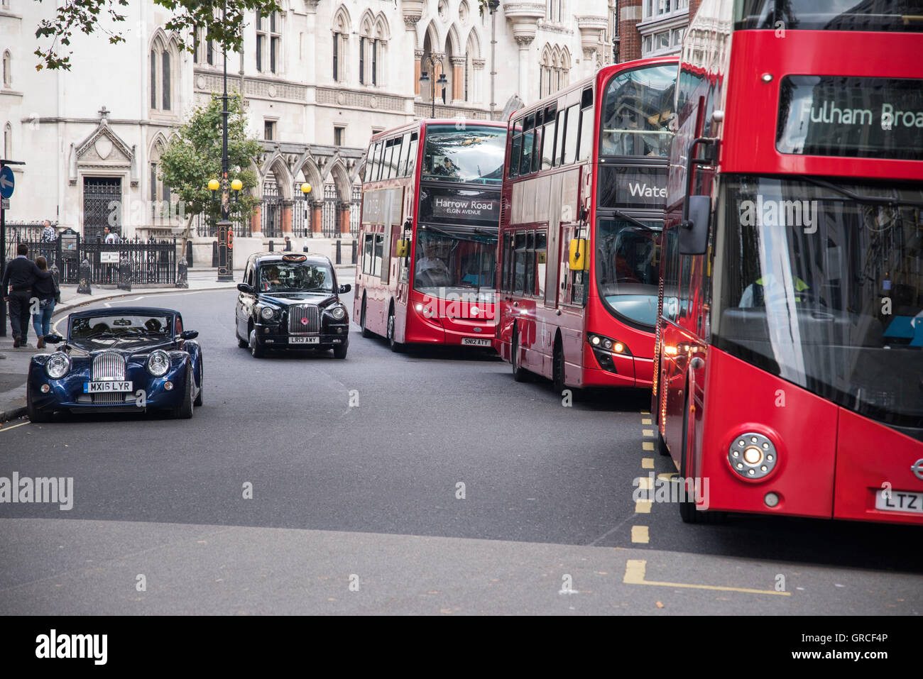 London Red Double Decker Buses, Black Cab Taxis and Morgan Sports Car. Traffic in Central London by the Strand. Stock Photo