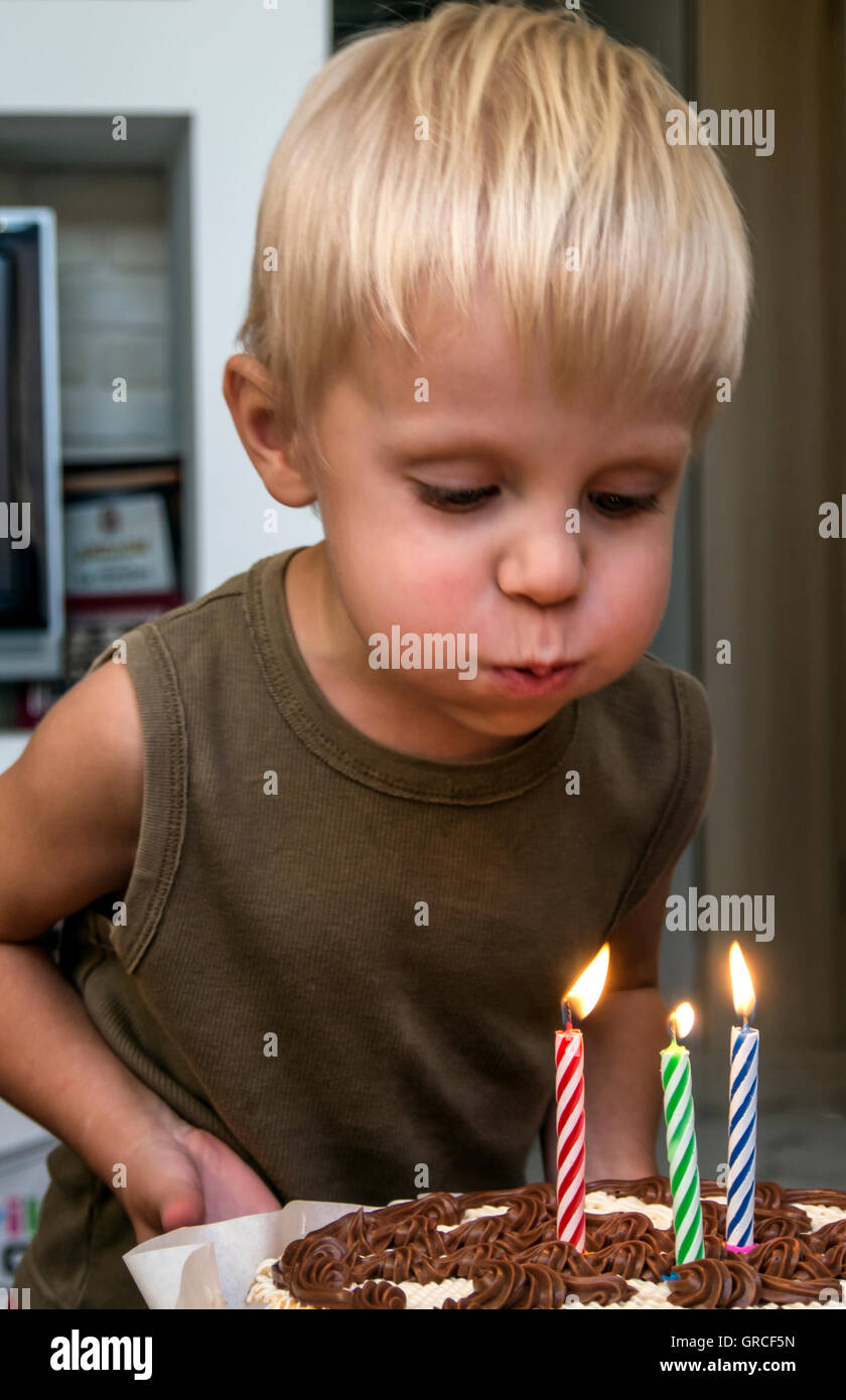 Beautiful adorable three year old boy celebrating his birthday, blowing